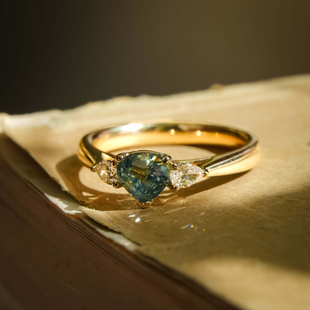 Pear cut green sapphire and diamond three stone engagement ring in yellow gold setting