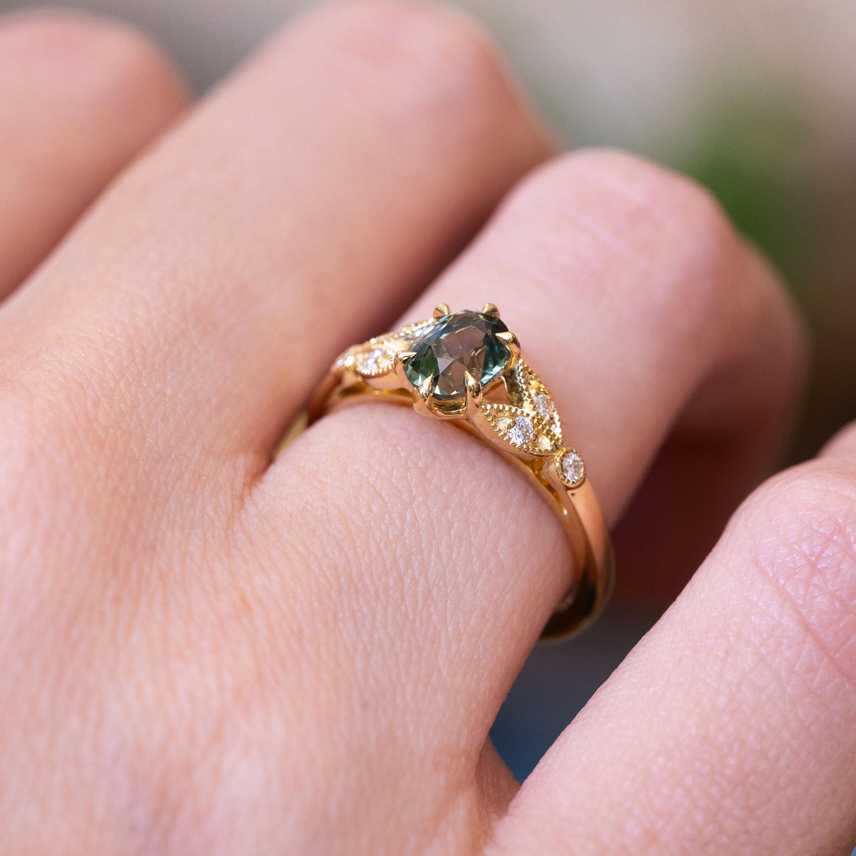 Pine green sapphire and diamond engagement ring with gold setting and diamond side stones.