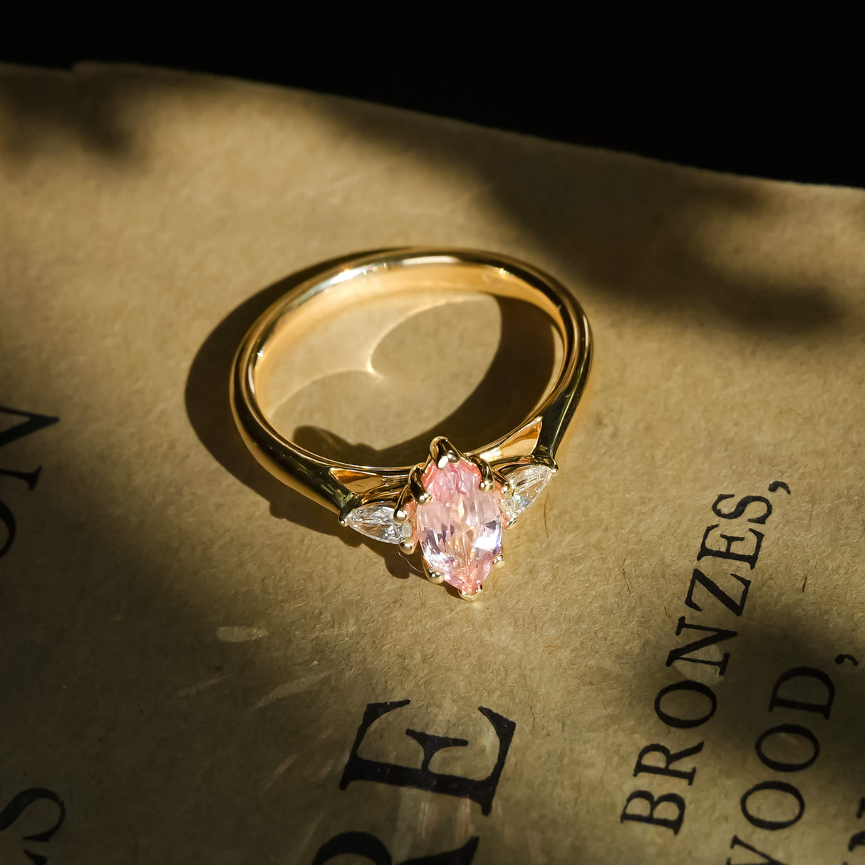 pink marquise cut sapphire and diamond three stone engagement ring in yellow gold