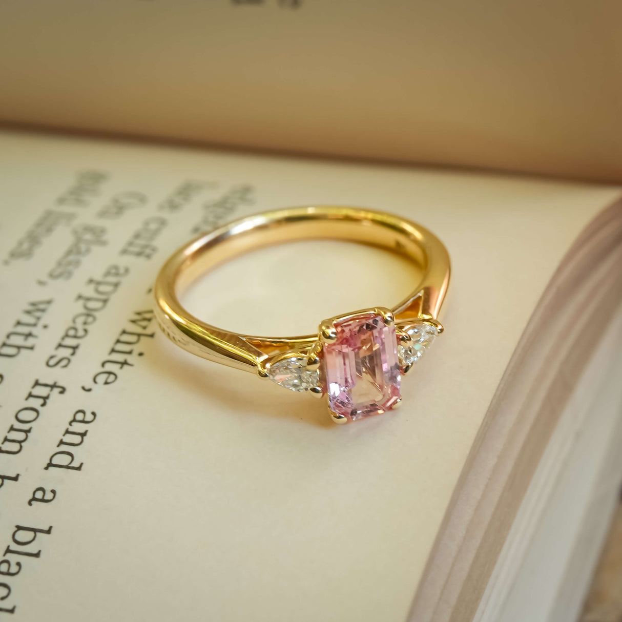 Pink sapphire and diamond three stone engagement ring in yellow gold band
