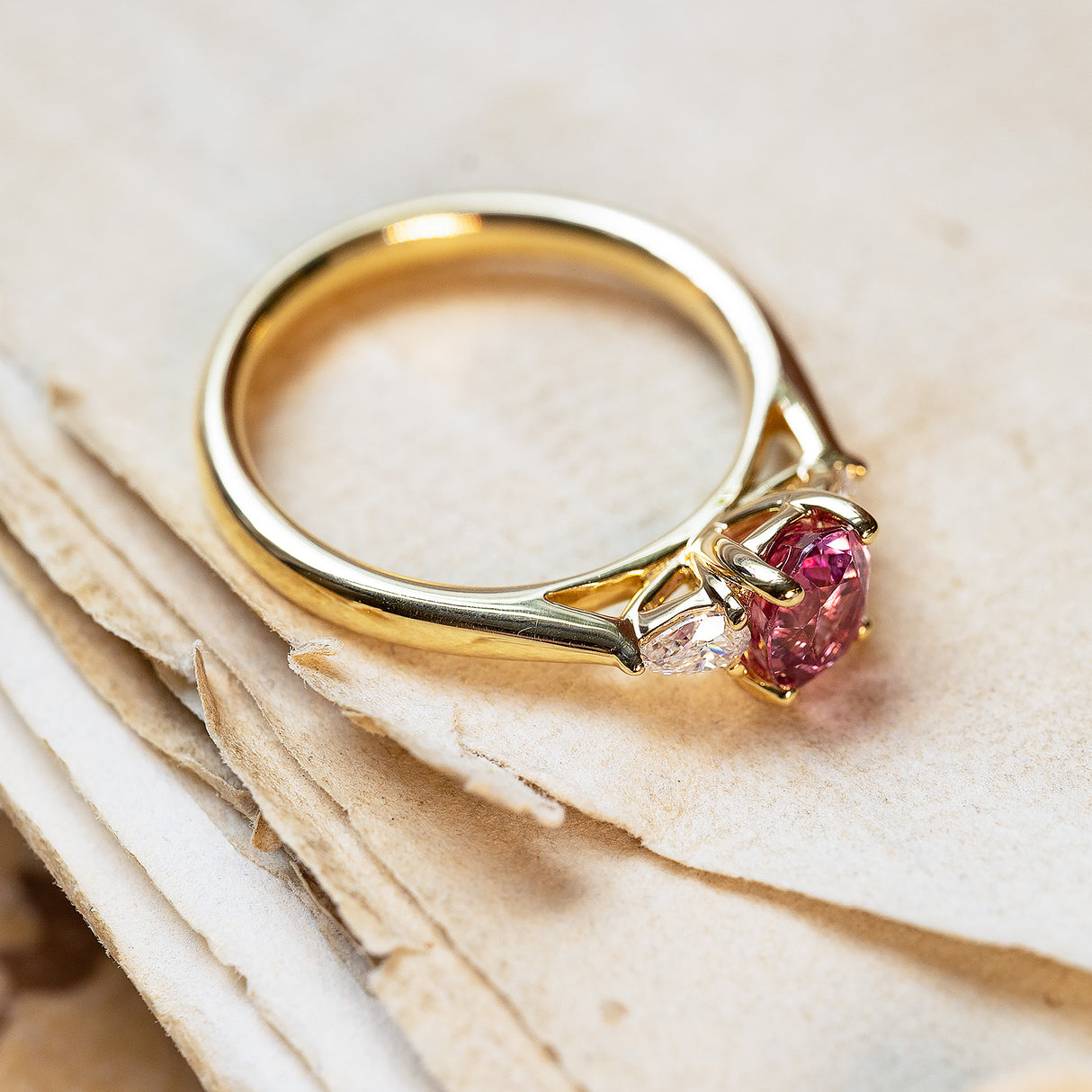 Pink sapphire and diamond three-stone engagement ring with oval pink sapphire centre stone.