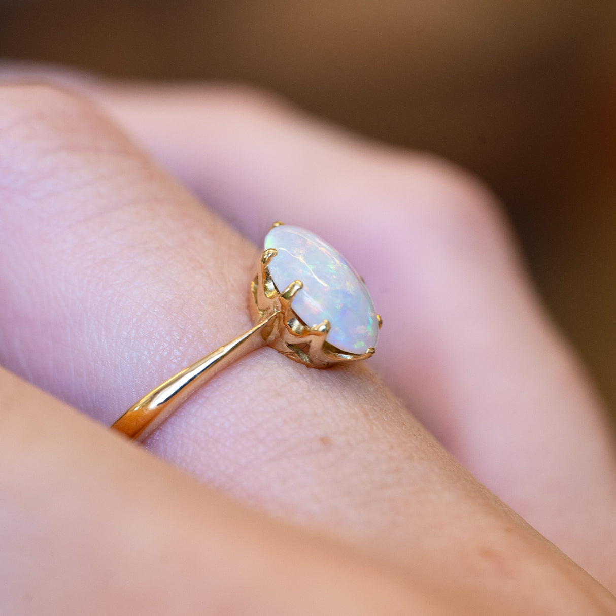 Precious opal solitaire ring showing raised gold setting and iridescent opal stone.