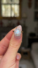 Edwardian opal and diamond cluster ring held in fingers and moved around to give perspective.