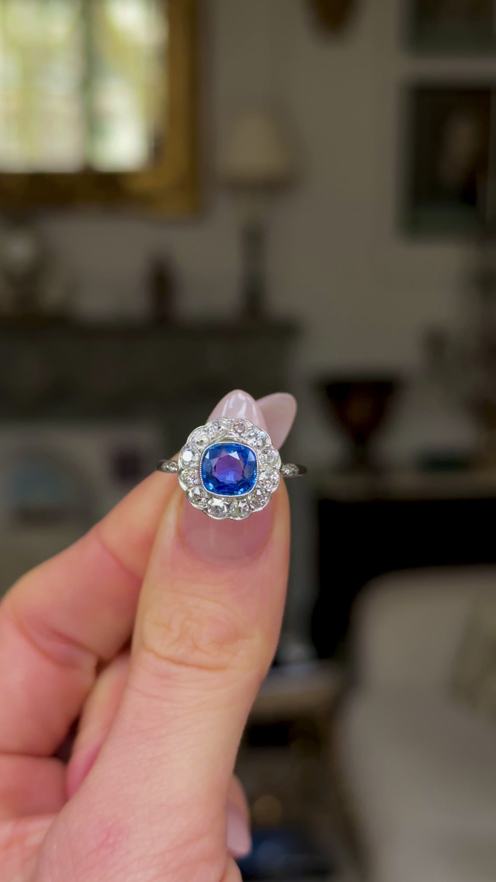 Vintage, 1940s Ceylon Cushion-Cut Sapphire and Diamond Cluster Engagement Ring, held in fingers and rotated to give perspective.