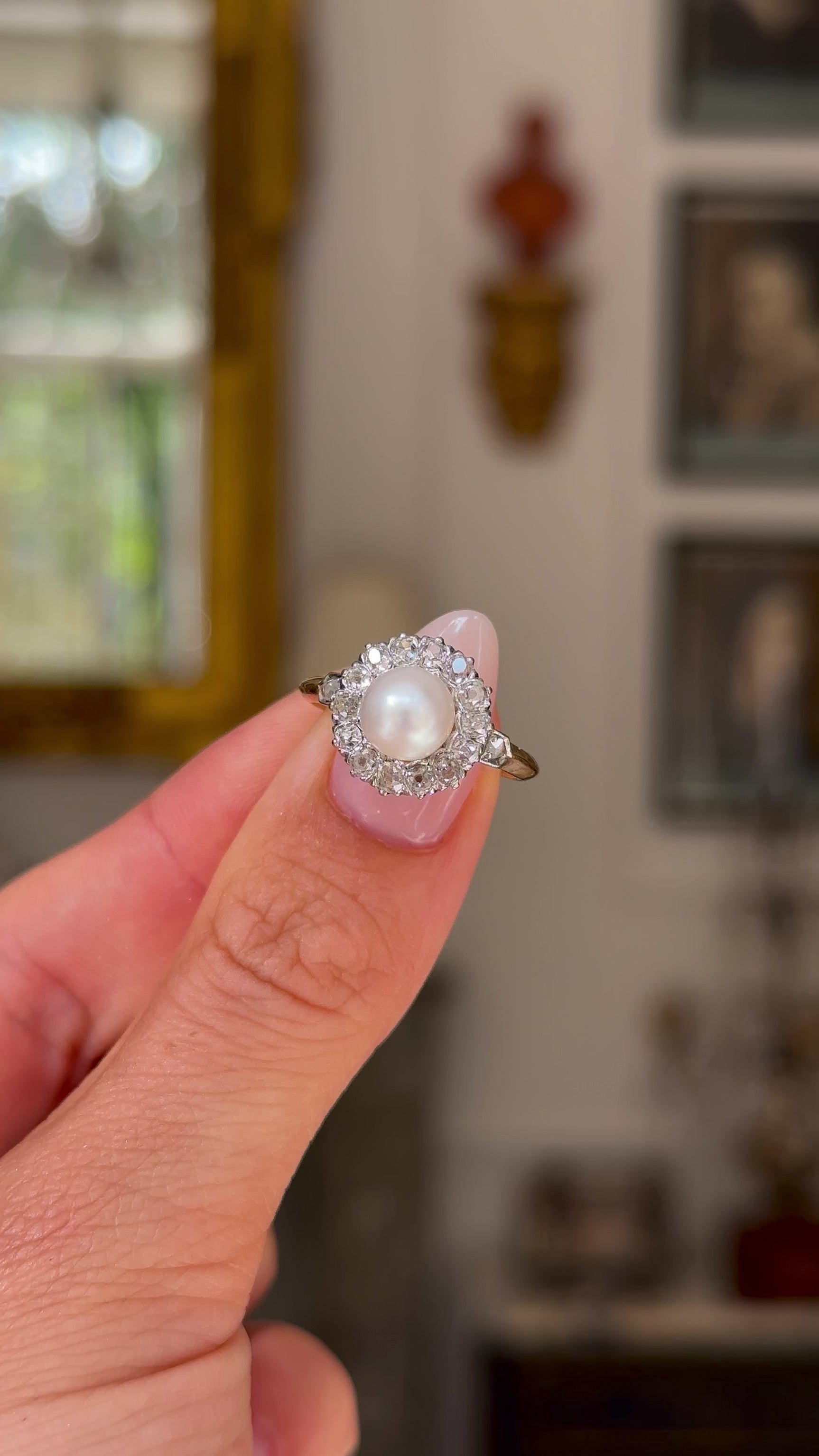 Antique pearl and diamond cluster ring held in fingers and moved around to give perspective.