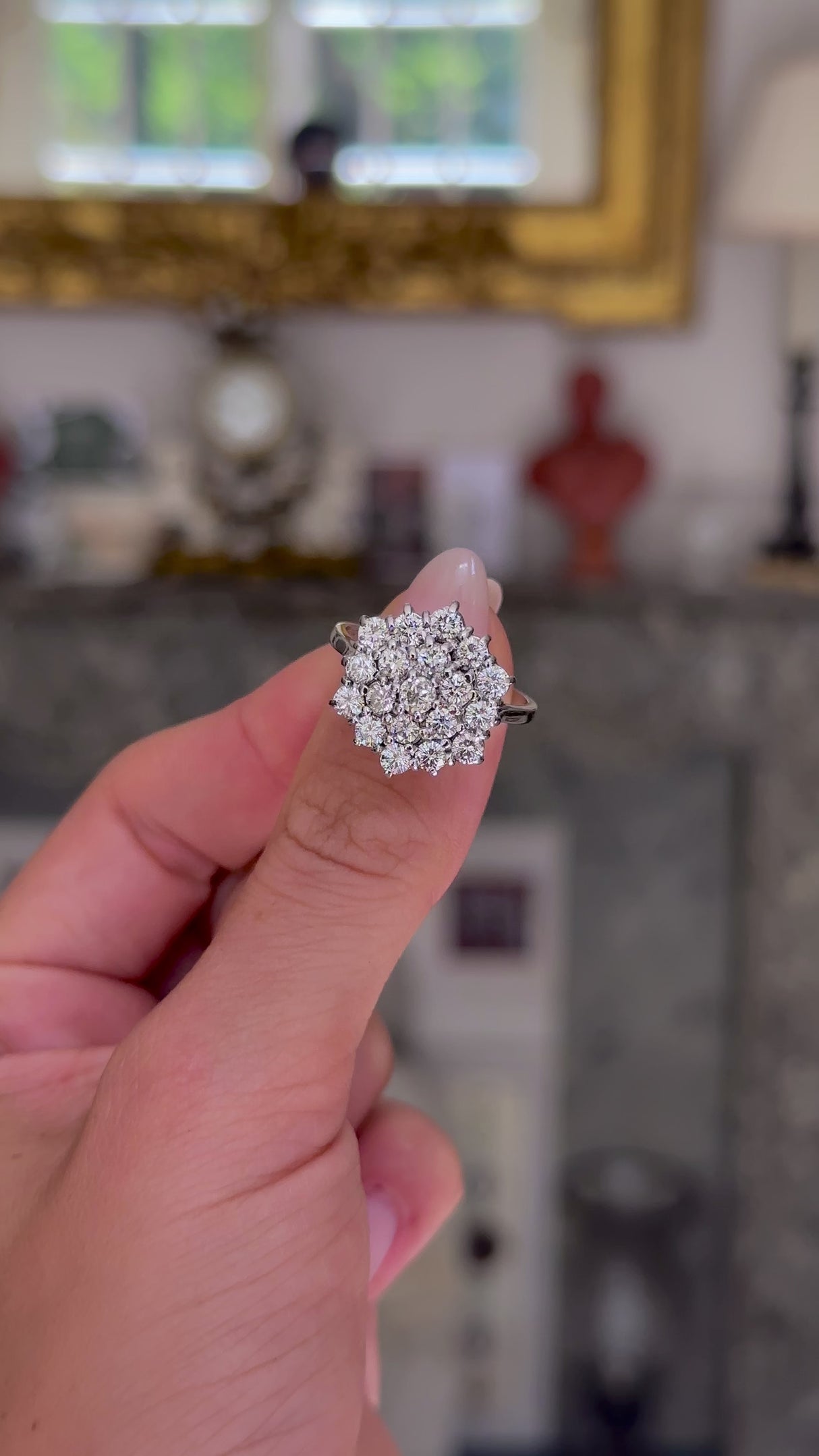 Vintage, large diamond cluster ring held in fingers and moved around to give perspective.
