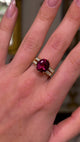 Red tourmaline and diamond cocktail ring, worn on hand and moved away from lens to give perspective, front view. 