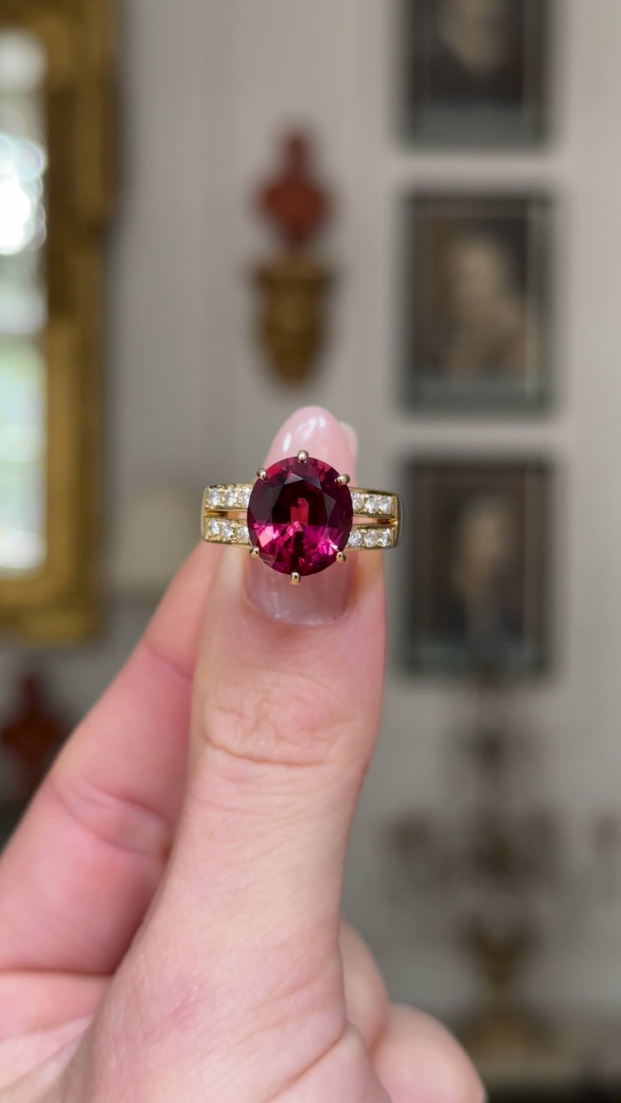 Red tourmaline and diamond cocktail ring, held in fingers and rotated to give perspective, front view. 