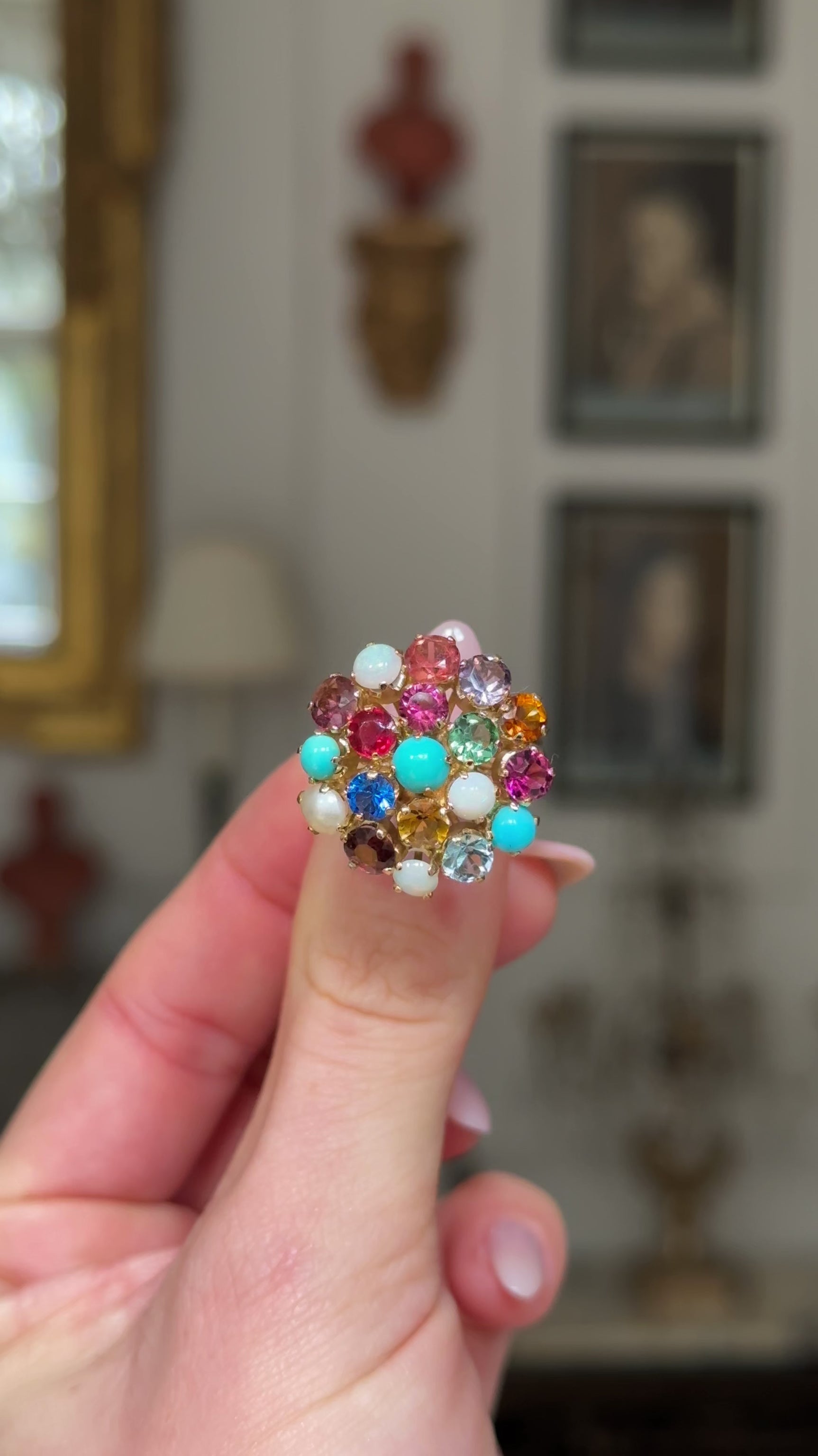 Multi gemstone cluster ring held in fingers and rotated to give full perspective, front view.