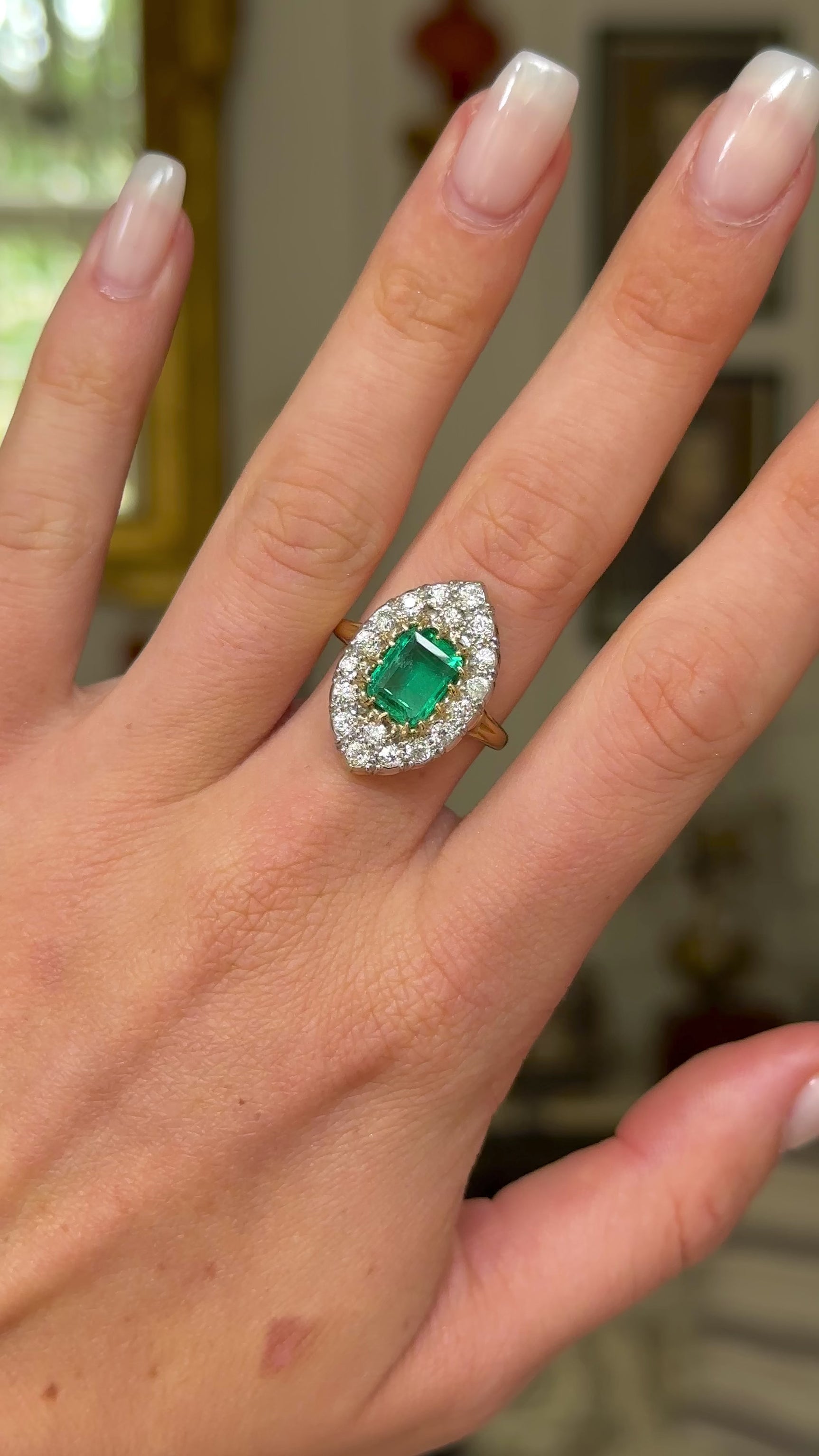 Emerald and diamond navette ring, worn on hand and rotated to give perspective.
