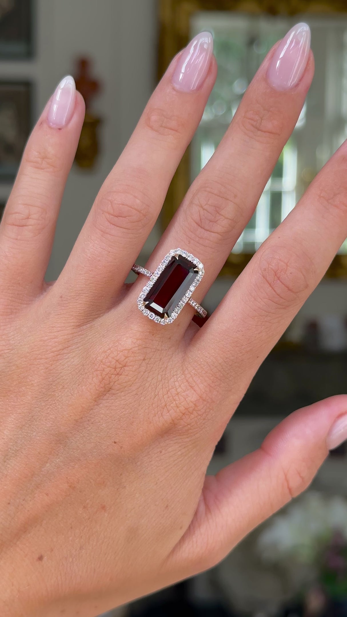 red garnet and diamond cluster ring worn on hand and moved away from lens to give perspective.