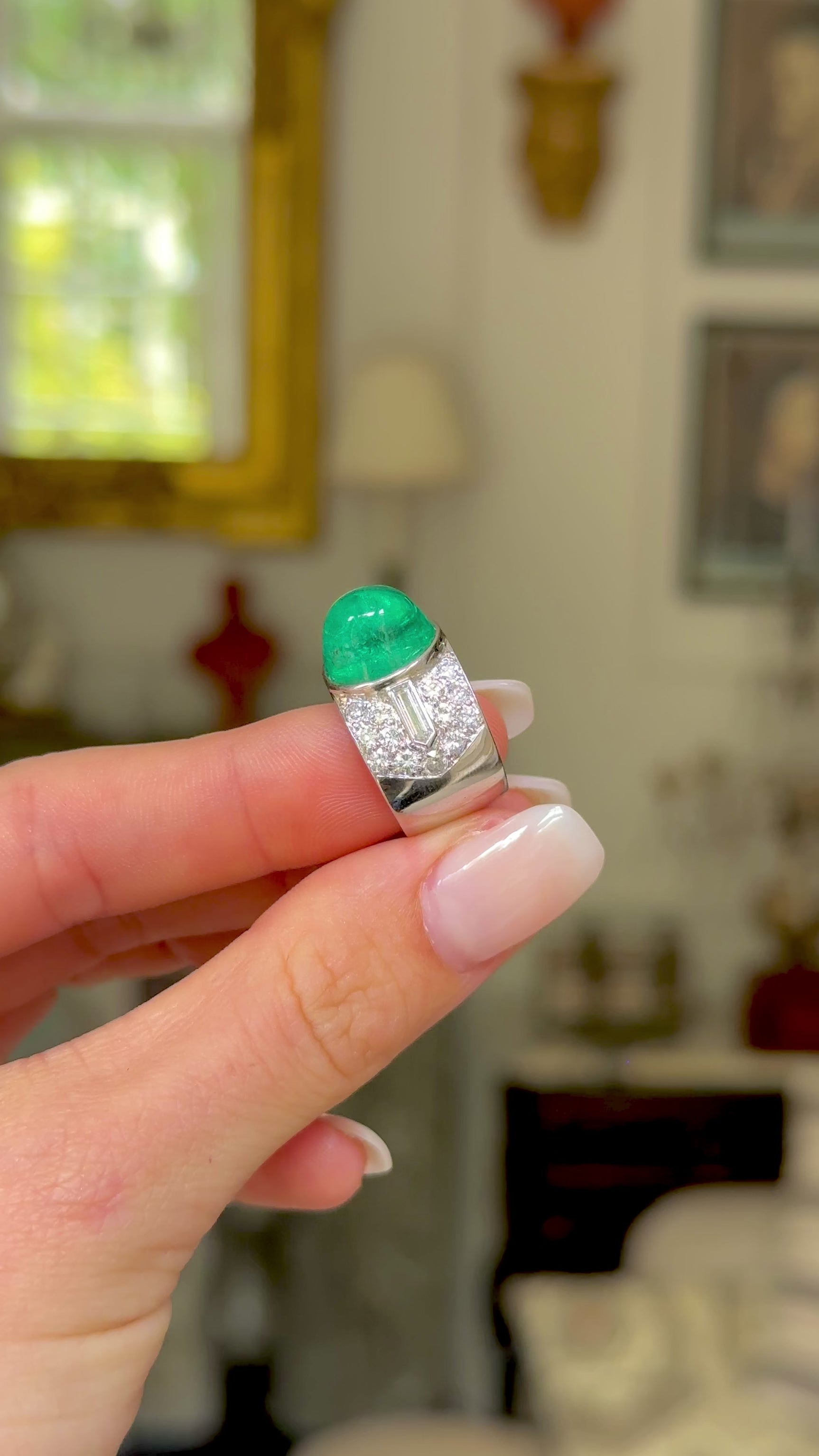 Trabert Hoeffer Mauboussin Art Deco emerald and diamond ring, held in fingers and rotated to give perspective.