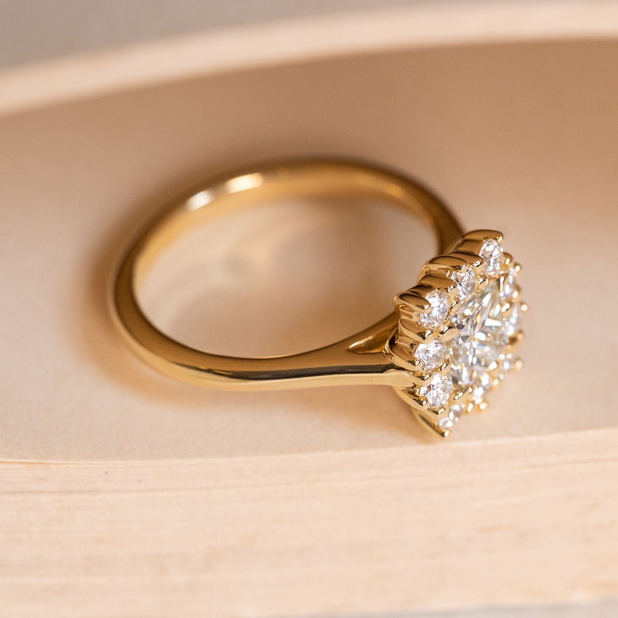 Antique inspired princess-cut diamond cluster engagement ring displaying the raised cluster setting and yellow gold band.