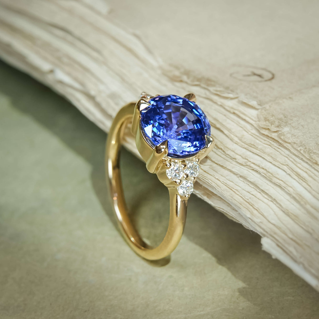 Round blue sapphire engagement ring with diamond trefoil sides and gold band