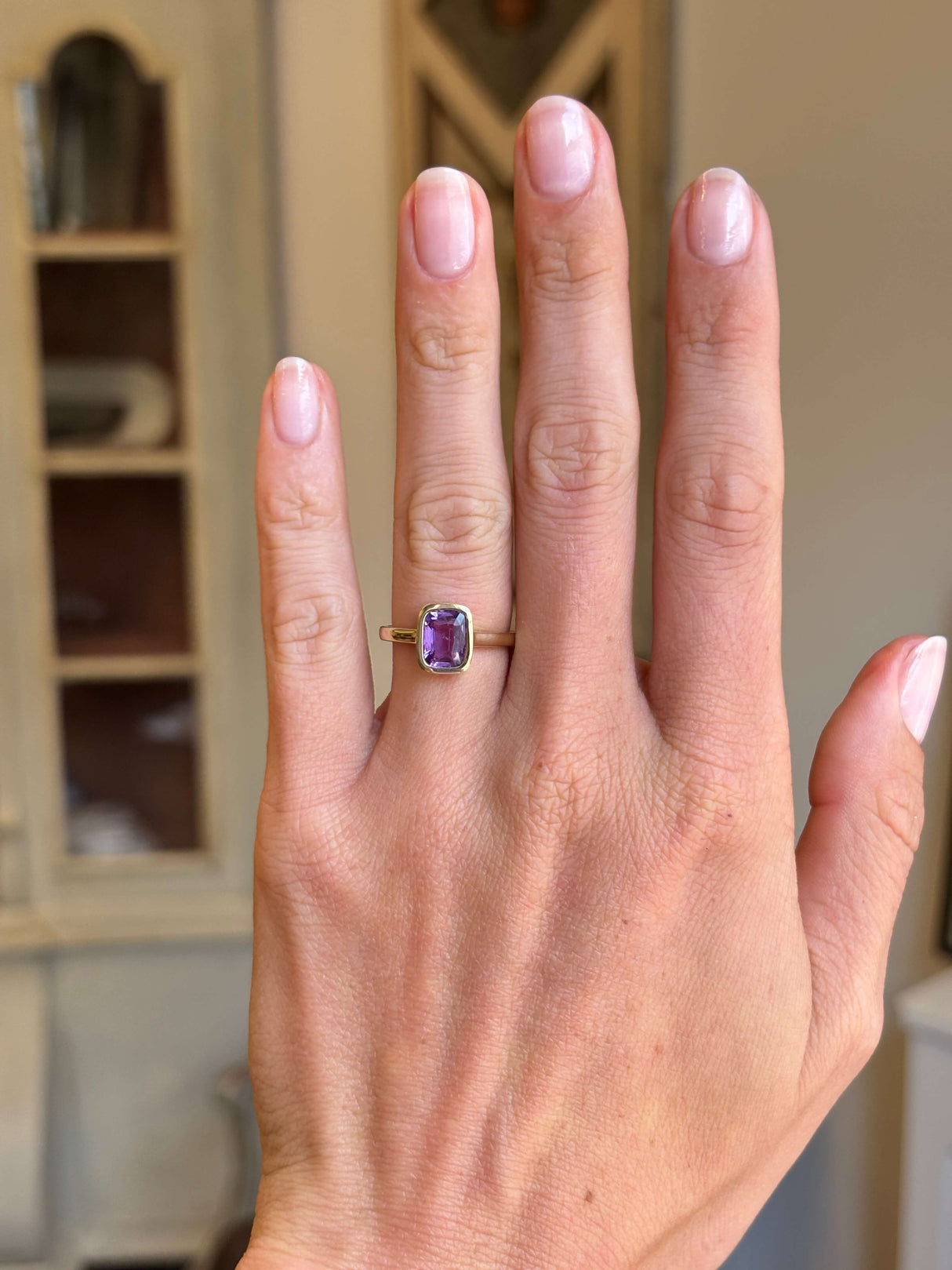 Royal purple cushion-cut sapphire solitaire engagement ring with a cushion-cut purple sapphire centre stone, displayed on a hand.