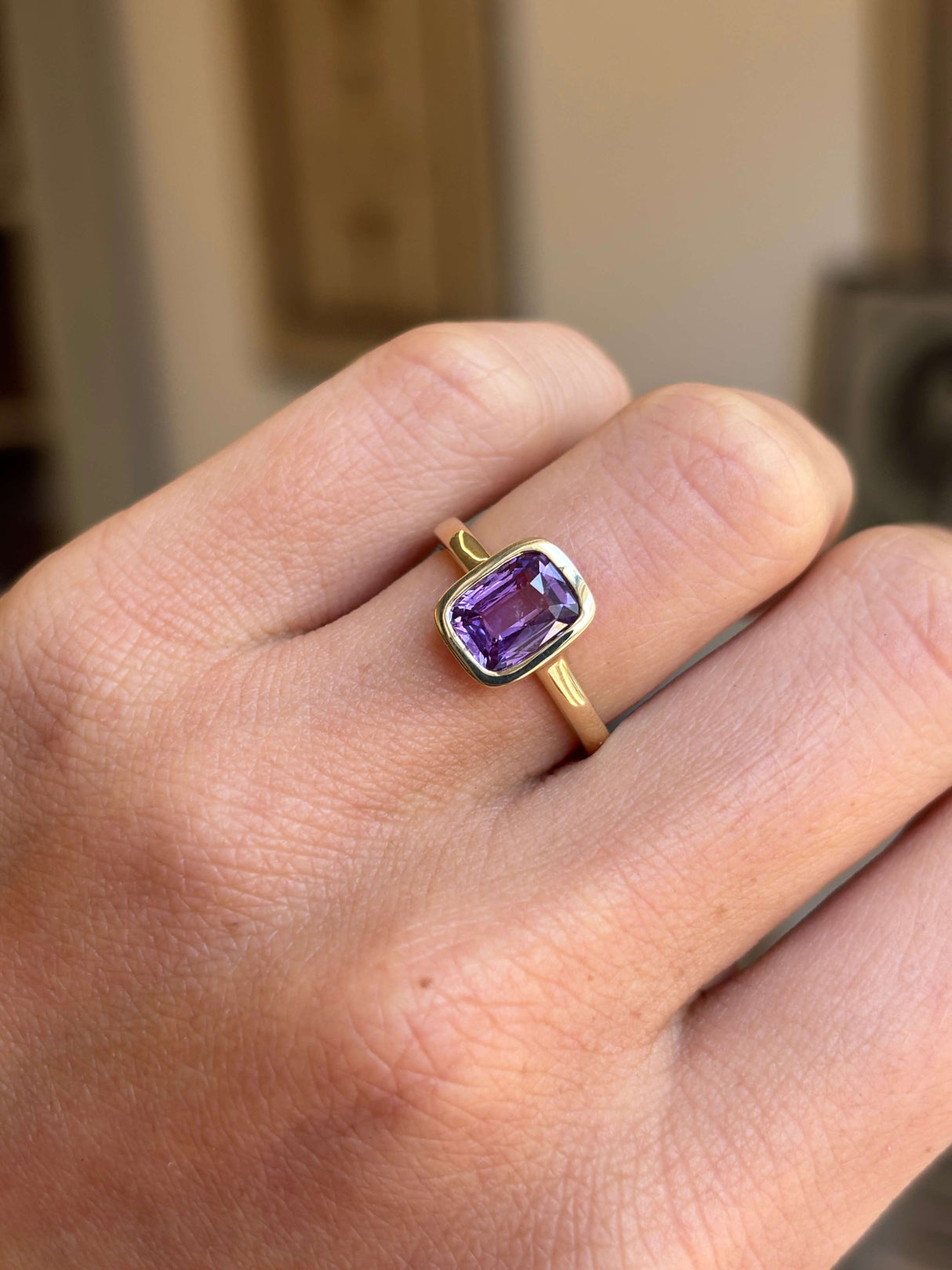 Royal purple cushion-cut sapphire solitaire engagement ring featuring a vibrant cushion-cut purple sapphire in a timeless solitaire design, worn on a hand.