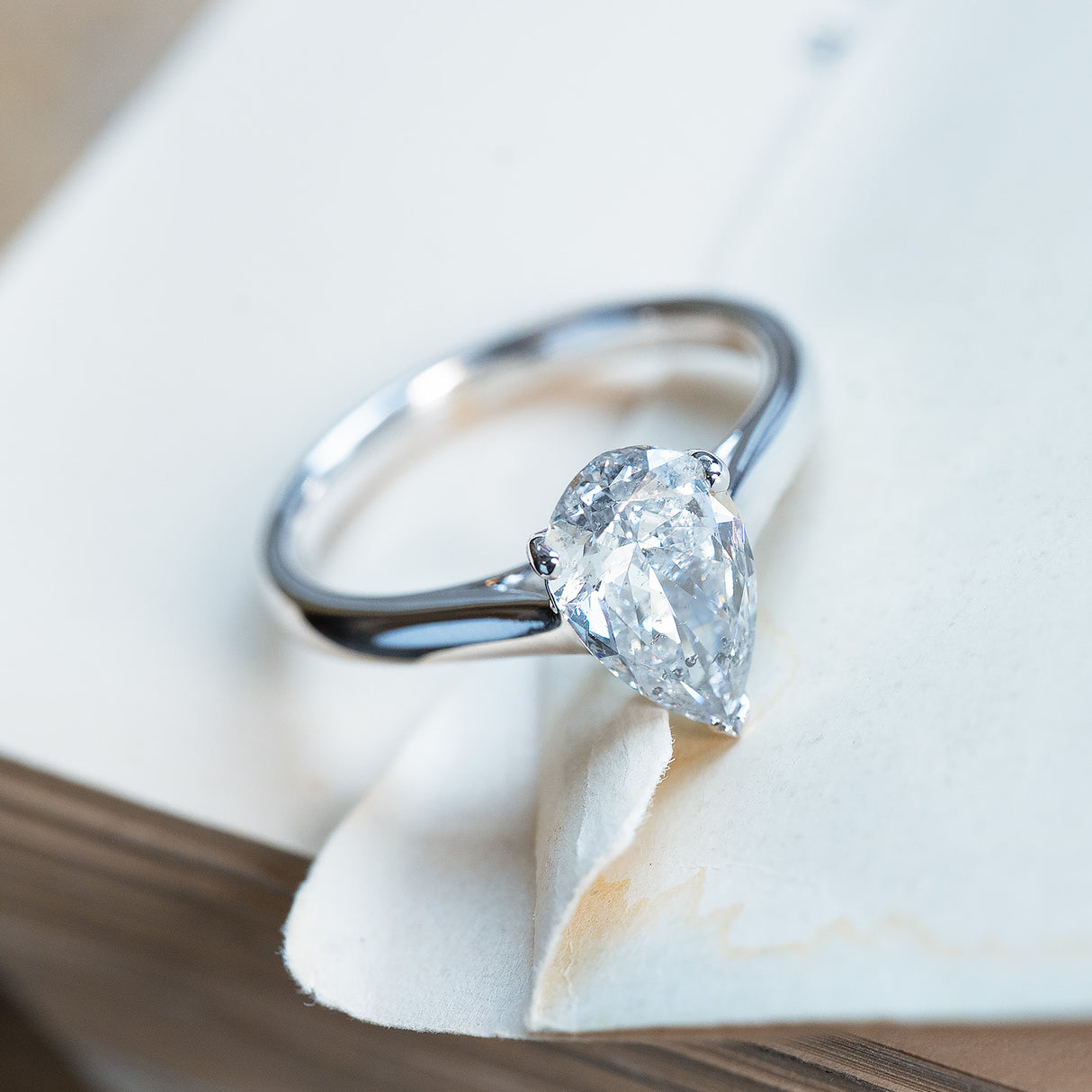 Vintage salt and pepper diamond solitaire ring with pear-shaped diamond in classic claw setting.