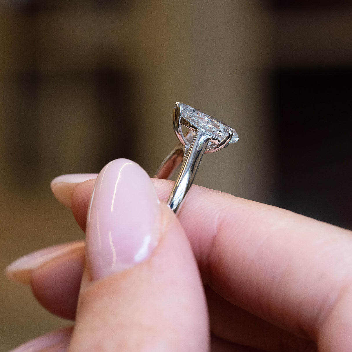 Vintage 1990s salt and pepper diamond solitaire ring held in hand showing open gallery beneath pear-shaped diamond.