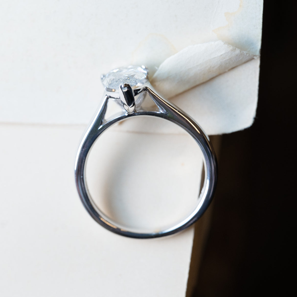 Vintage salt and pepper diamond solitaire ring with open gallery beneath pear-shaped diamond setting.