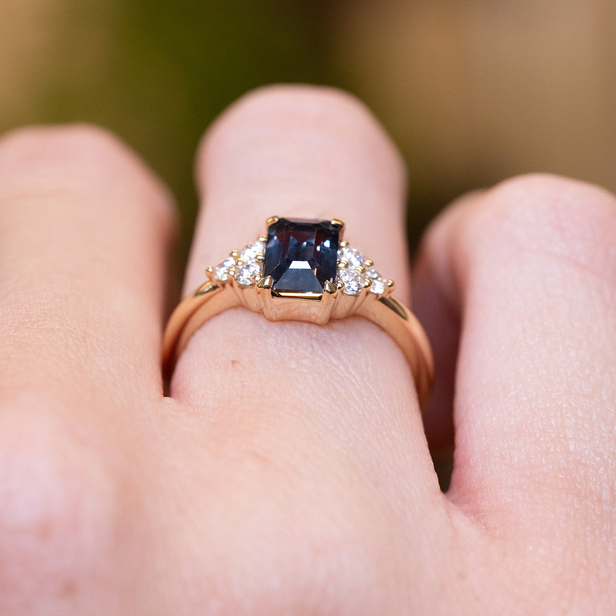 Teal sapphire and diamond cluster tre-foil engagement ring with gold band and diamond side clusters.