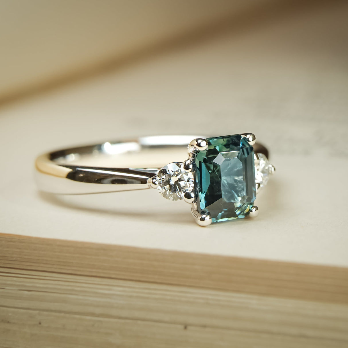 Teal sapphire three stone diamond ring with platinum setting