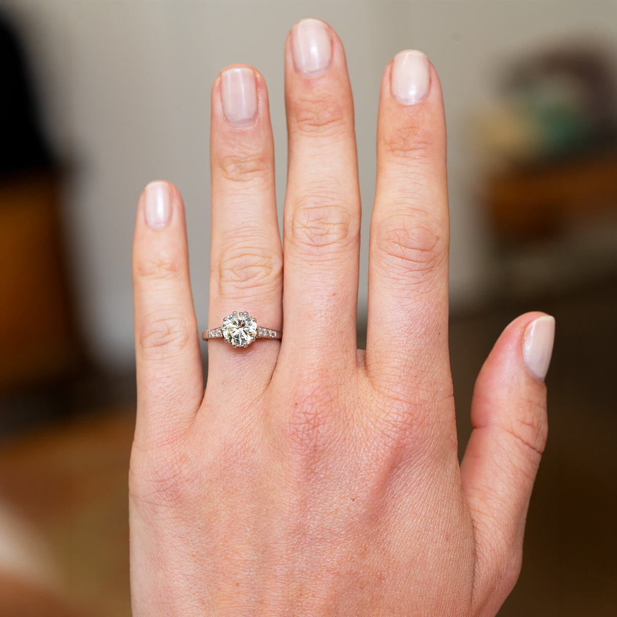 Hand wearing a tinted yellow diamond ring with a blurred background.