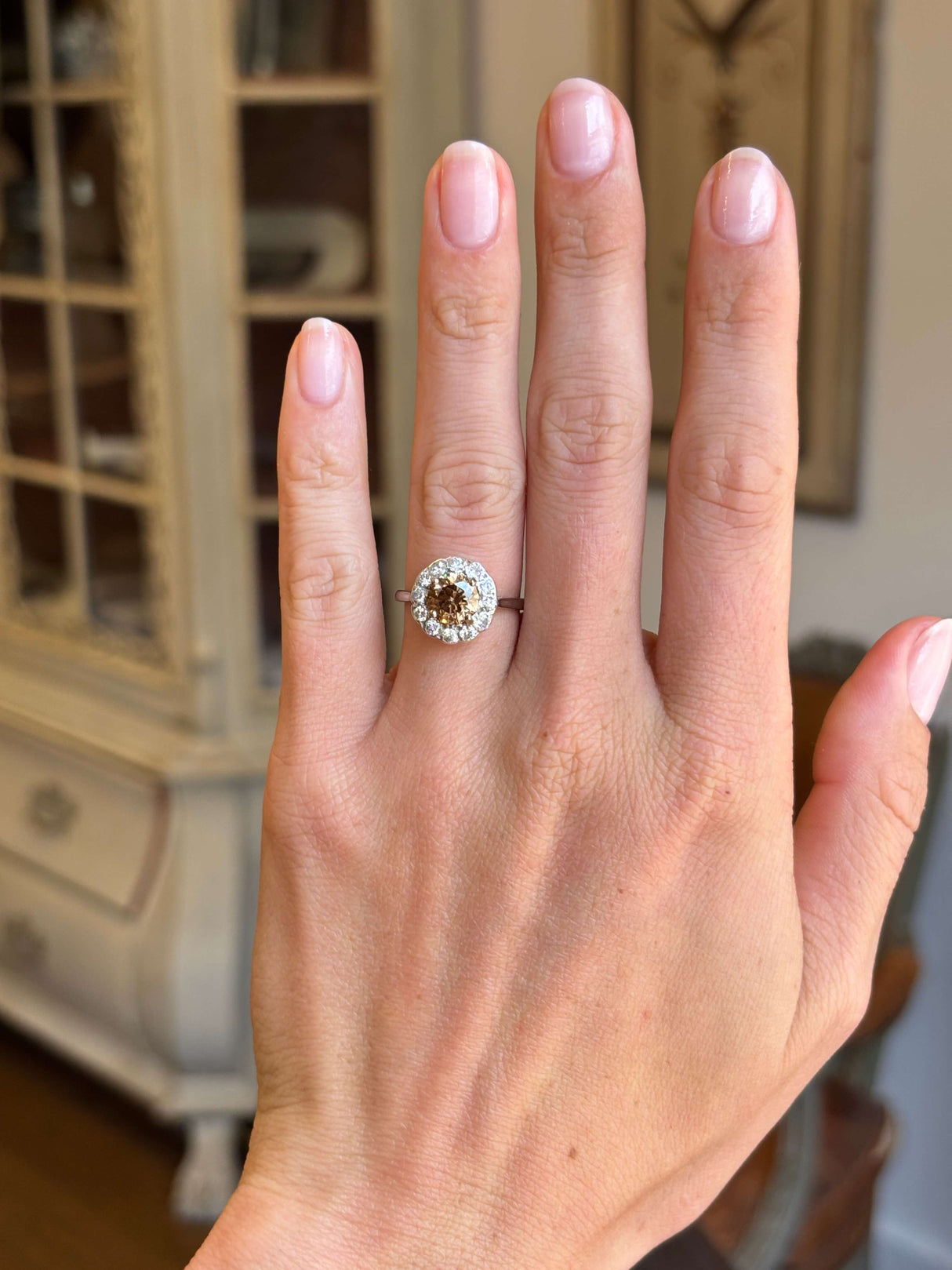 Vintage 1950s cinnamon brown diamond cluster engagement ring with a cinnamon brown diamond centre stone and diamond halo, displayed on a hand.