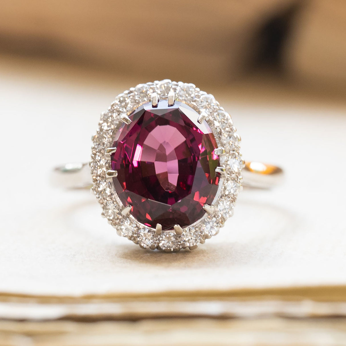 Vintage 1960s garnet and diamond cluster ring with oval garnet centre stone and diamond halo.