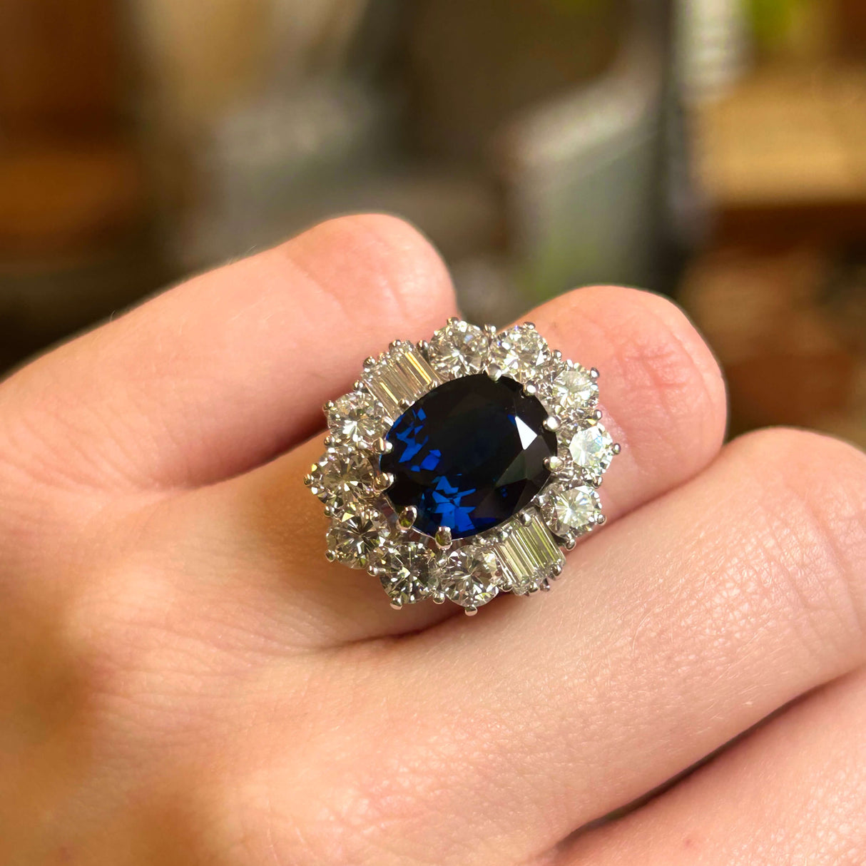Large oval sapphire and diamond cluster ring worn on hand.