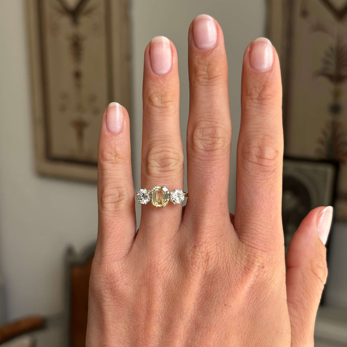 Vintage 1970s yellow sapphire and old-cut diamond three-stone engagement ring with a yellow sapphire centre and old-cut diamond side stones, displayed on a hand.