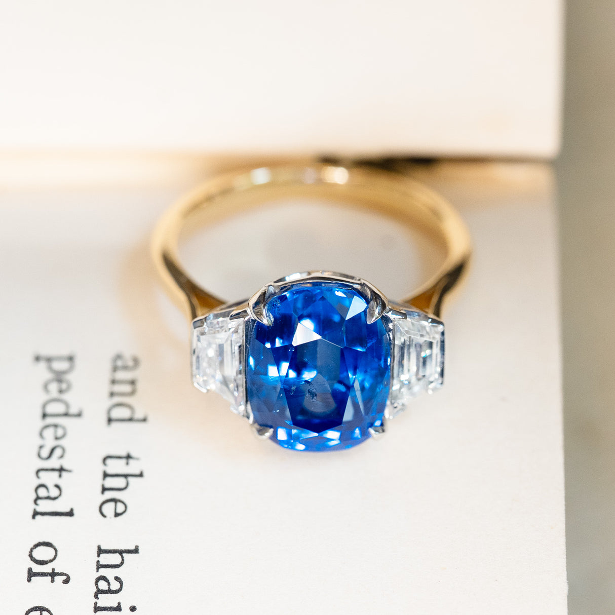 Vintage 1990s sapphire and diamond three-stone ring displayed on antique book pages.