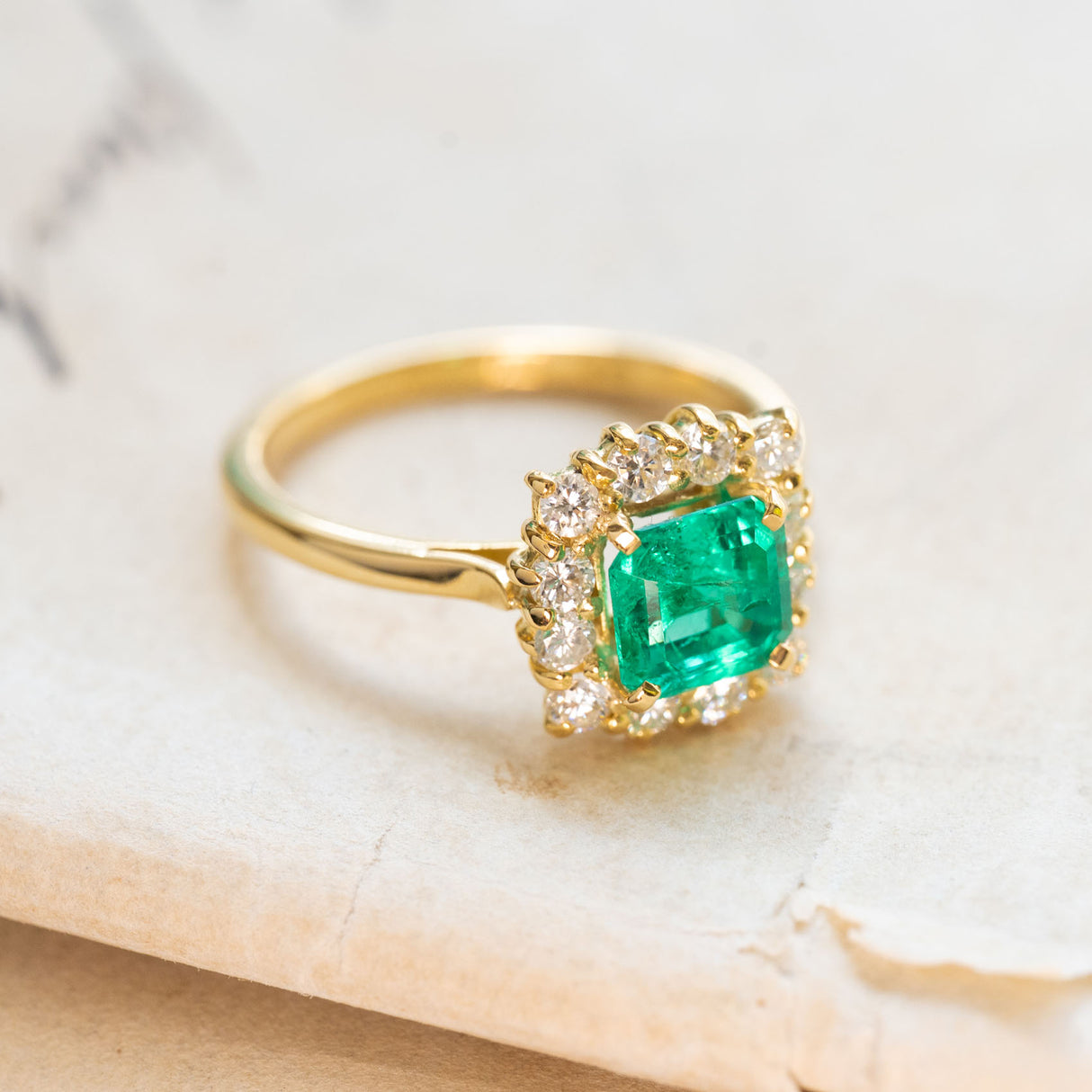 Vintage 1980s Colombian emerald and diamond cluster ring in polished yellow gold.