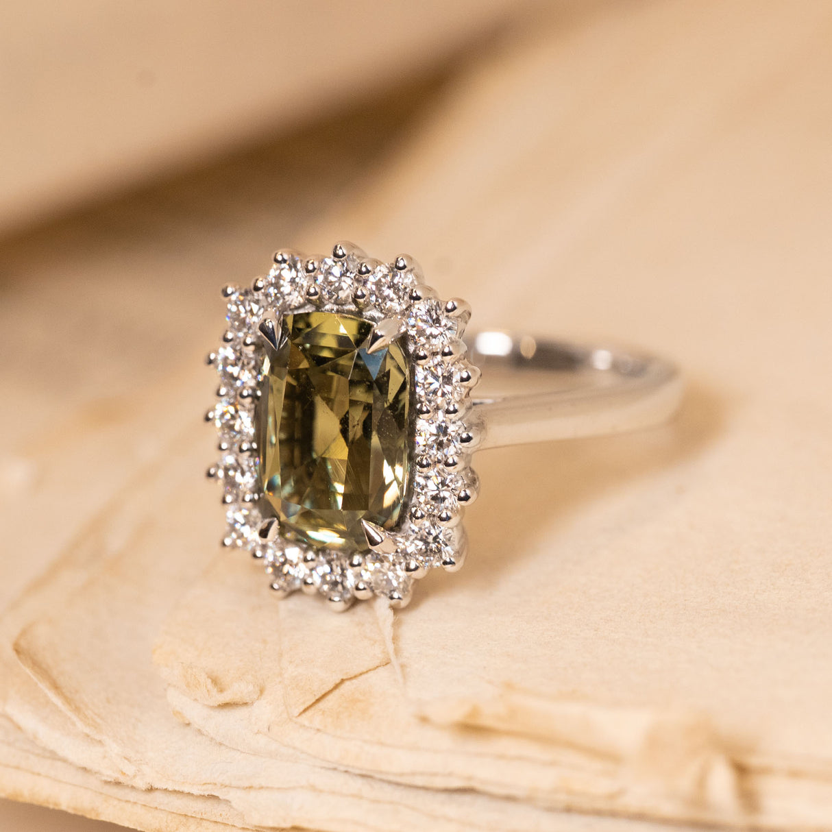 Vintage green sapphire and diamond halo ring showcasing a rectangular cushion-cut green sapphire framed by sparkling round diamonds in white gold.