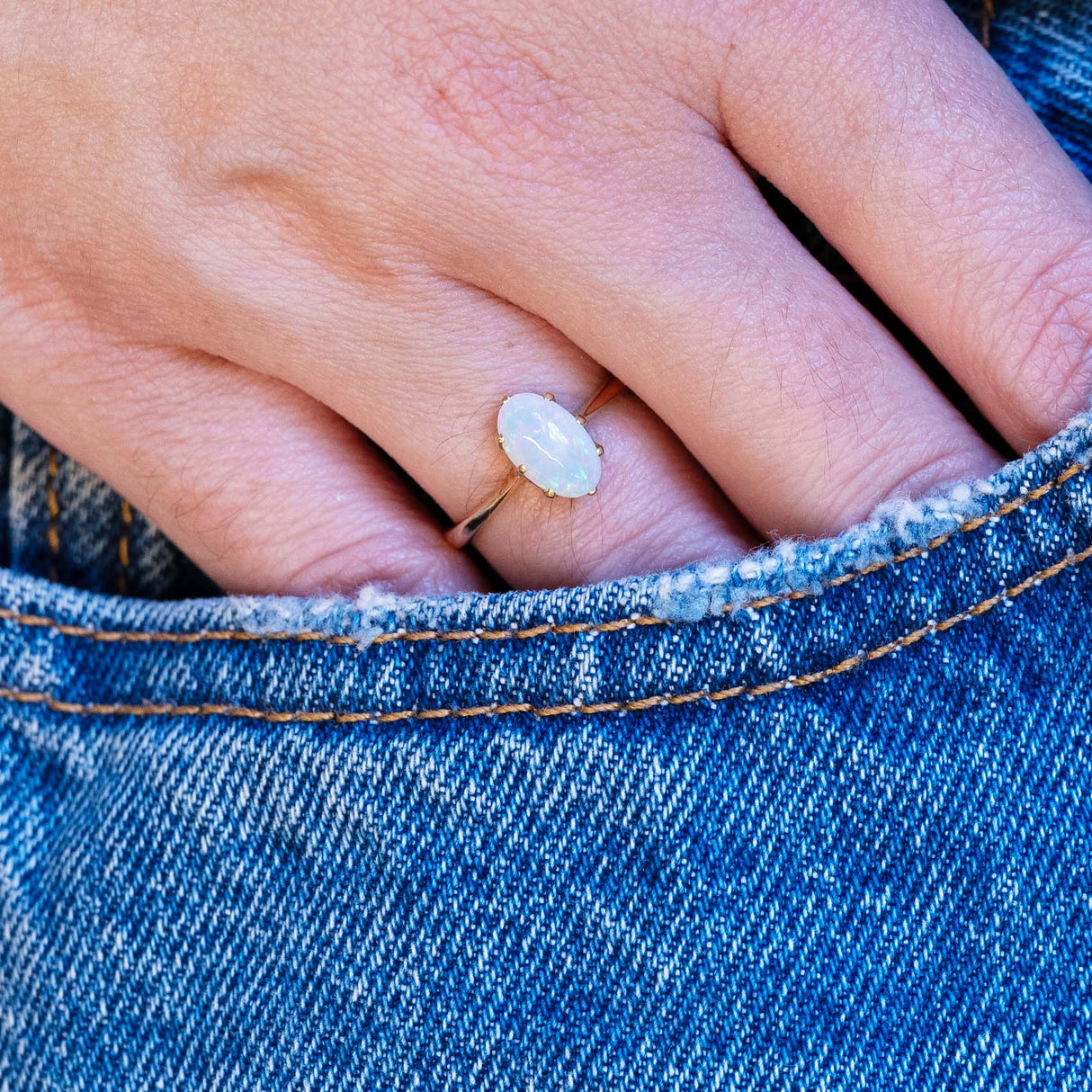 Vintage precious opal solitaire ring styled with denim pocket.