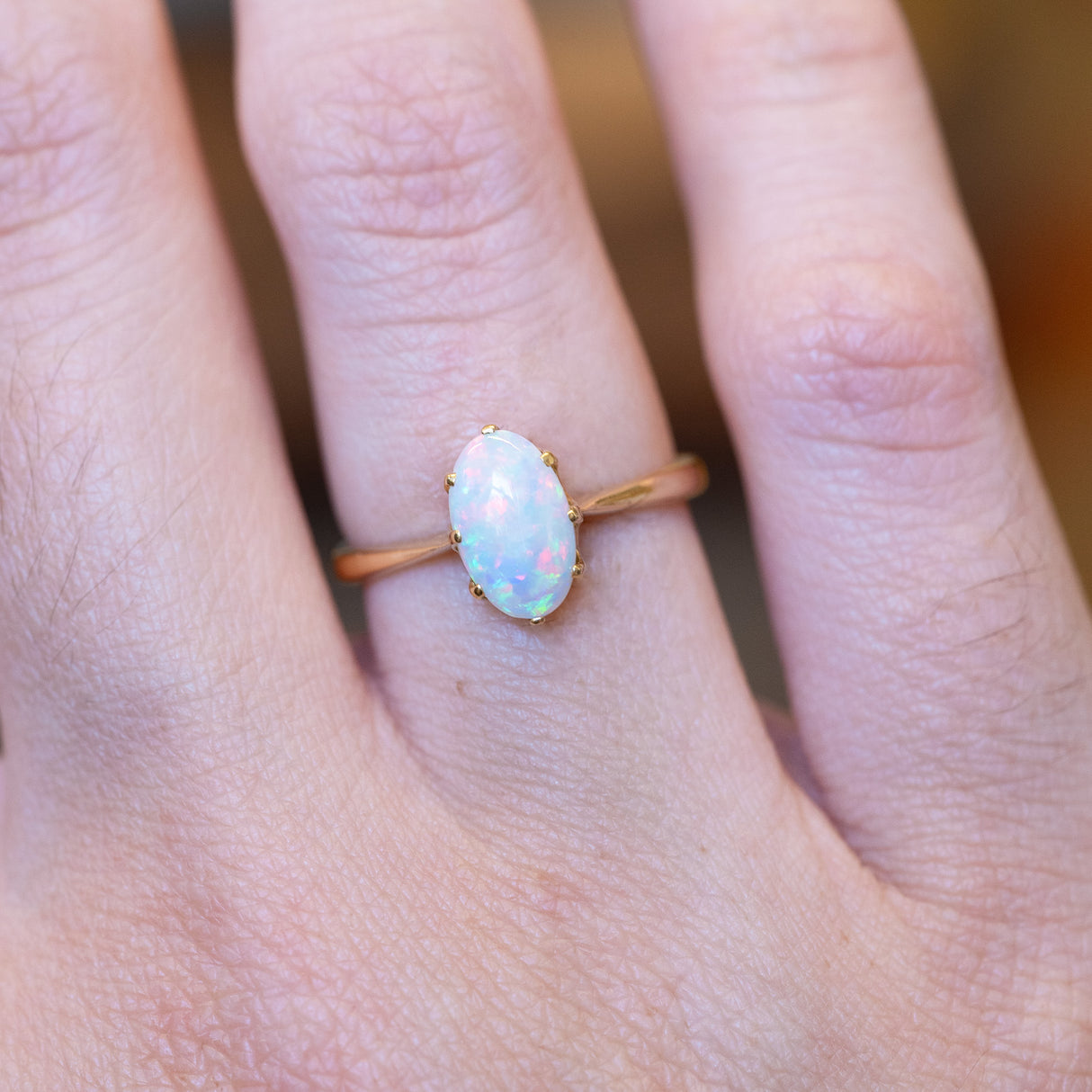 Vintage precious opal solitaire ring with oval opal gemstone and gold band.