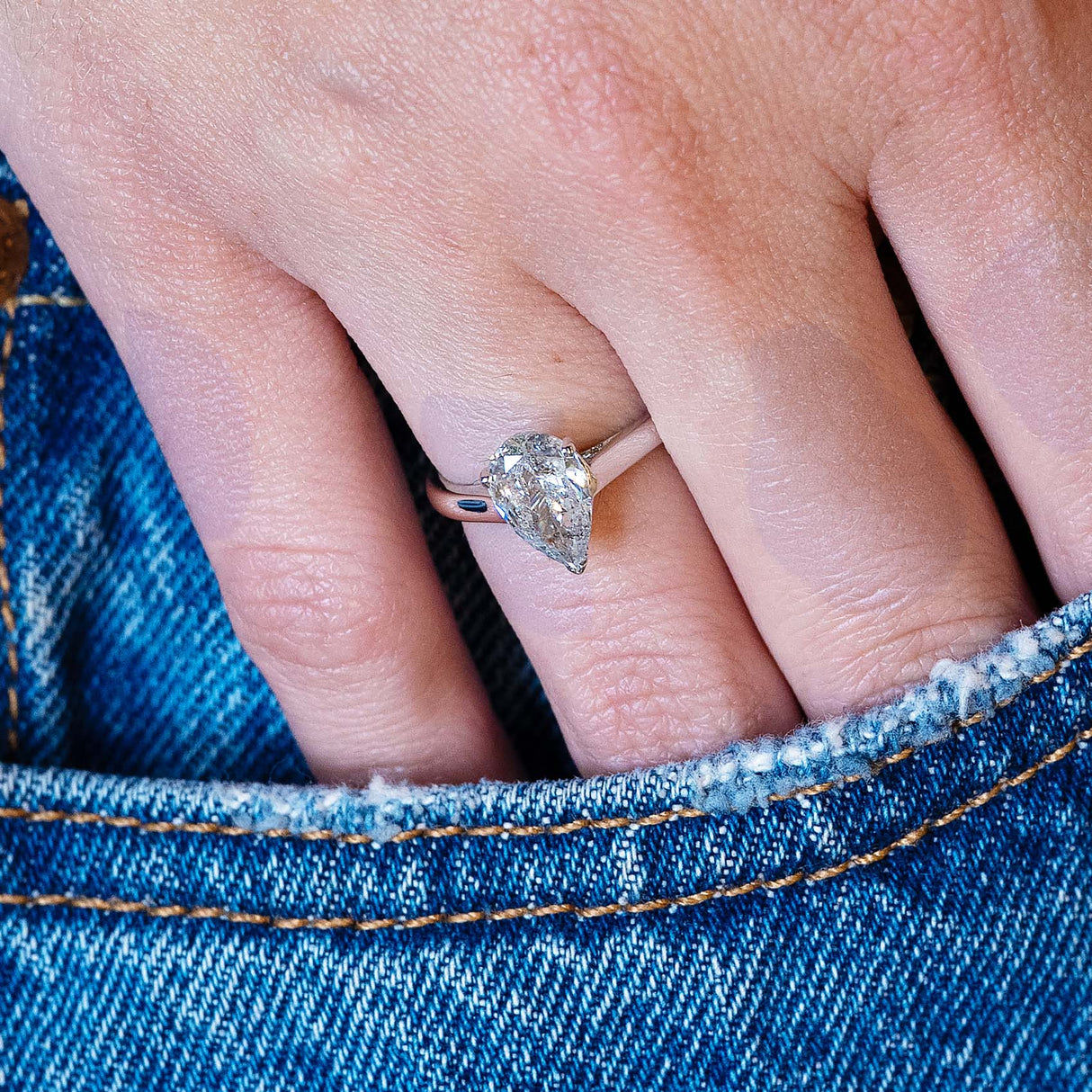 Vintage salt and pepper diamond solitaire ring worn on hand with denim pocket styling.