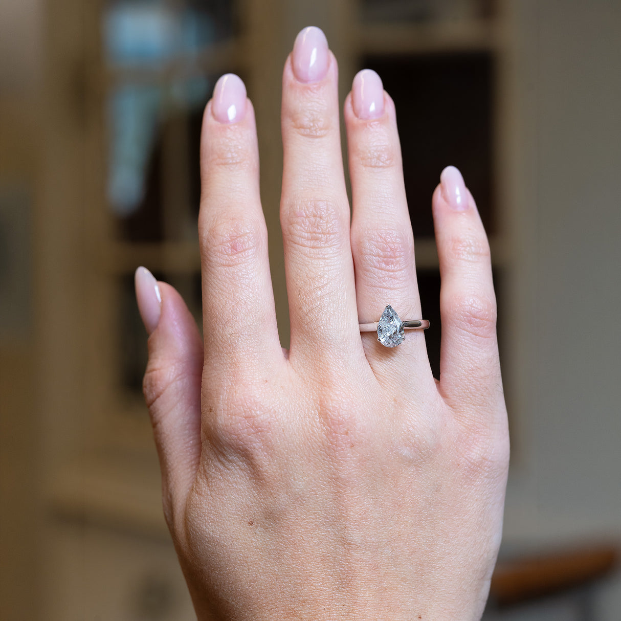 Vintage 1990s salt and pepper diamond solitaire ring worn on hand with pear-shaped diamond and metal band.