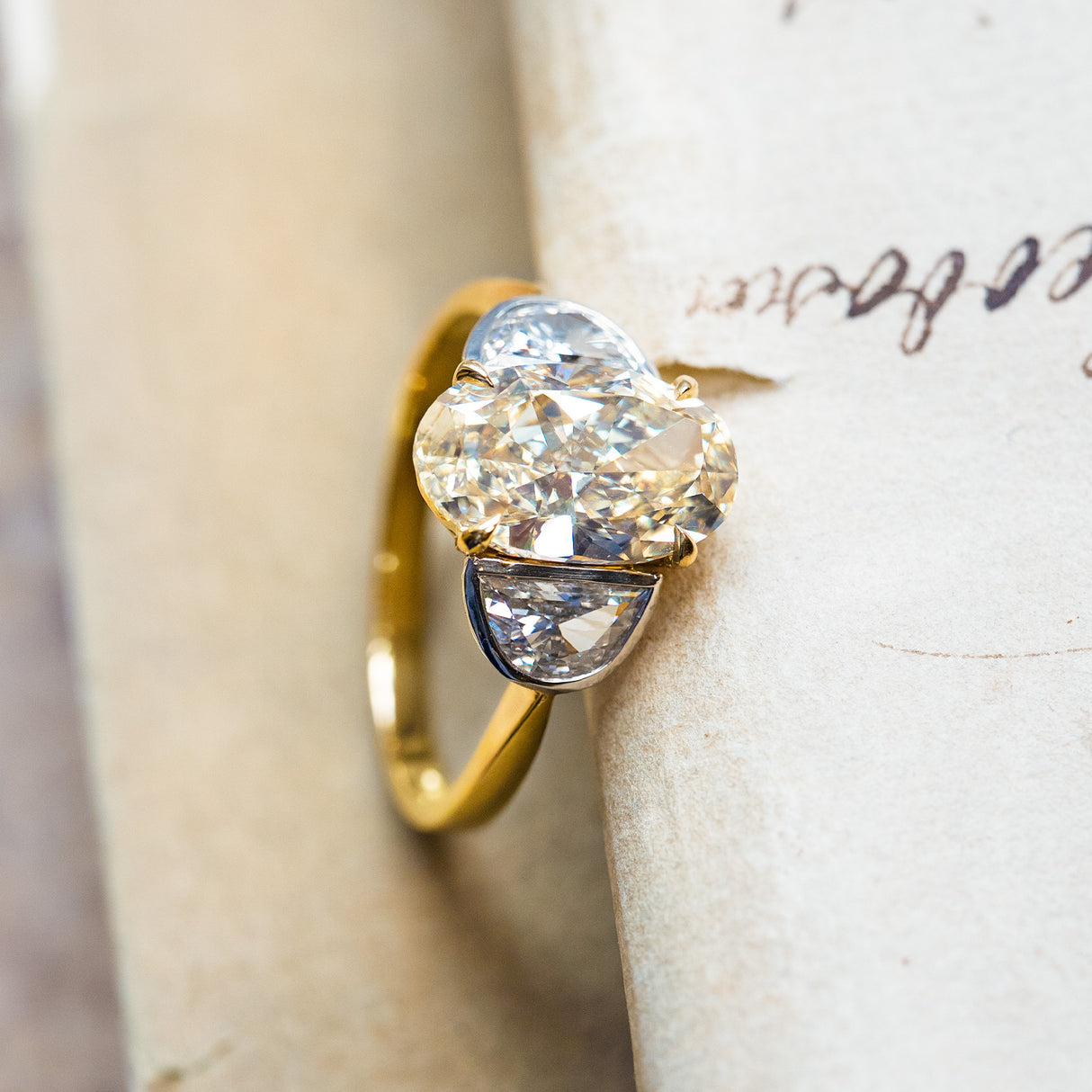 Vintage yellow oval diamond three-stone ring with bright half-moon diamonds and slim gold band.