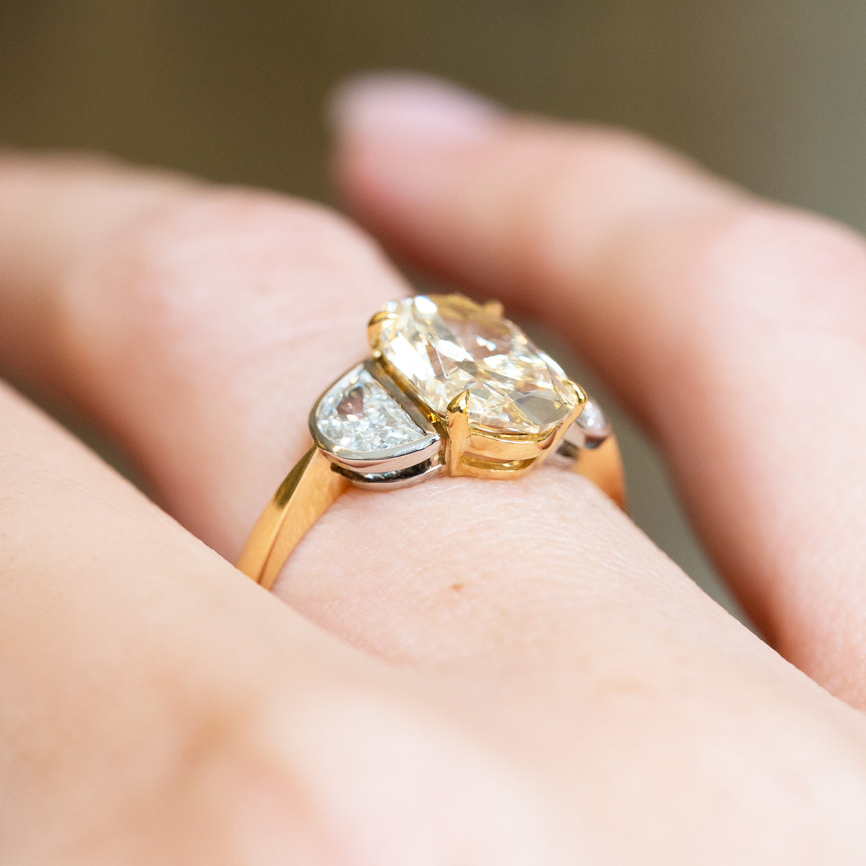 Vintage yellow oval diamond and half-moon diamond three-stone ring with elevated gold setting and curved side diamonds.