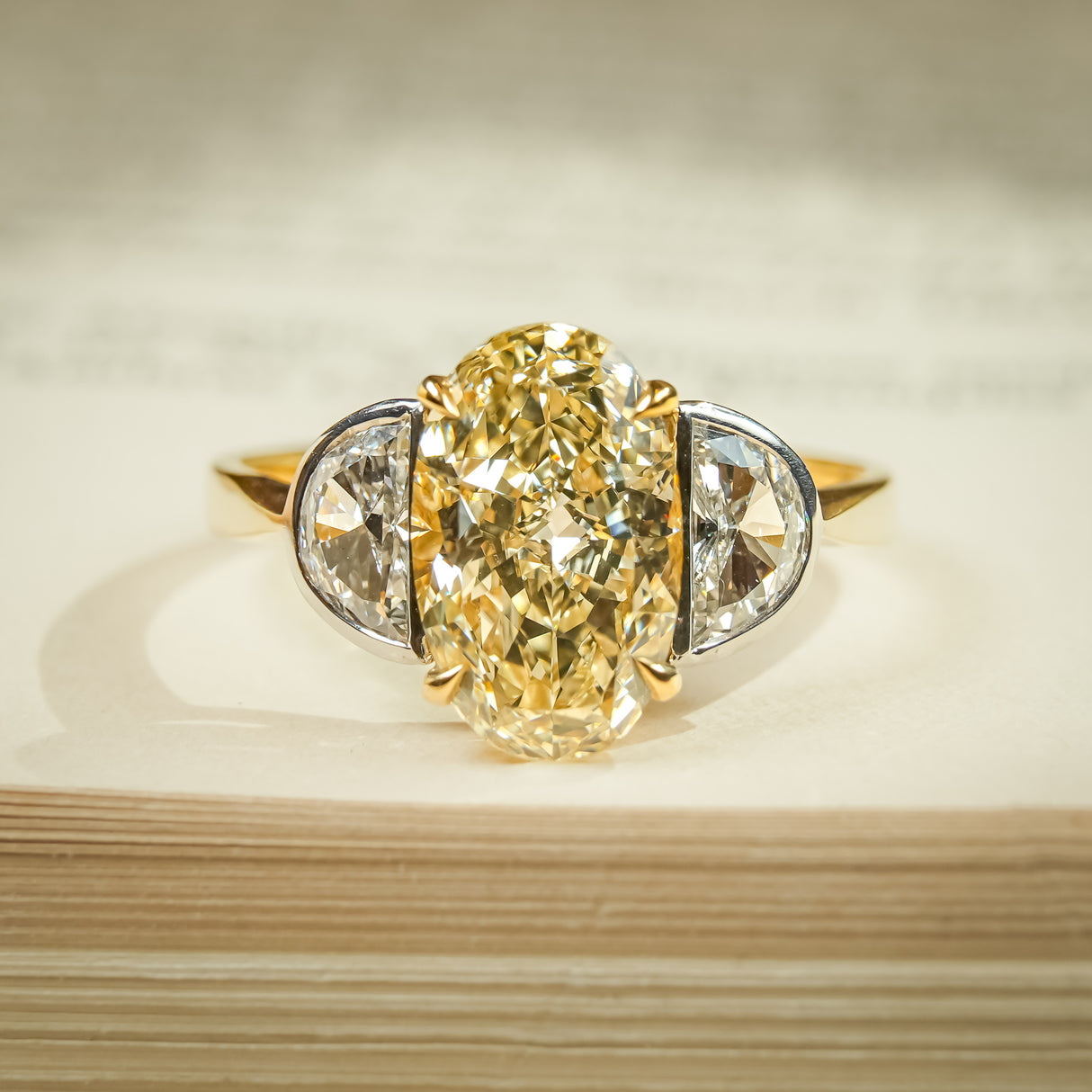 Yellow diamond three stone ring with oval center and half moon side stones