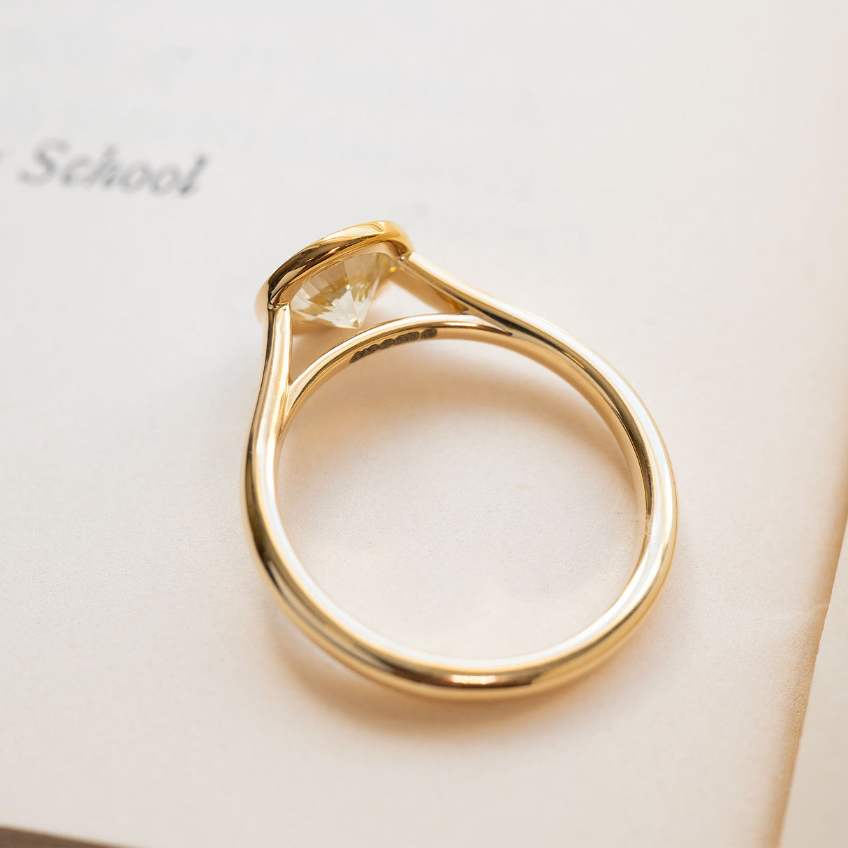 Diamond rub-over solitaire engagement ring in polished yellow gold with round brilliant-cut diamond.