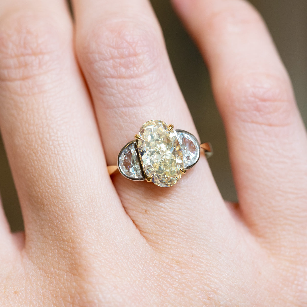 Vintage yellow oval diamond ring with half-moon side diamonds and polished gold setting.