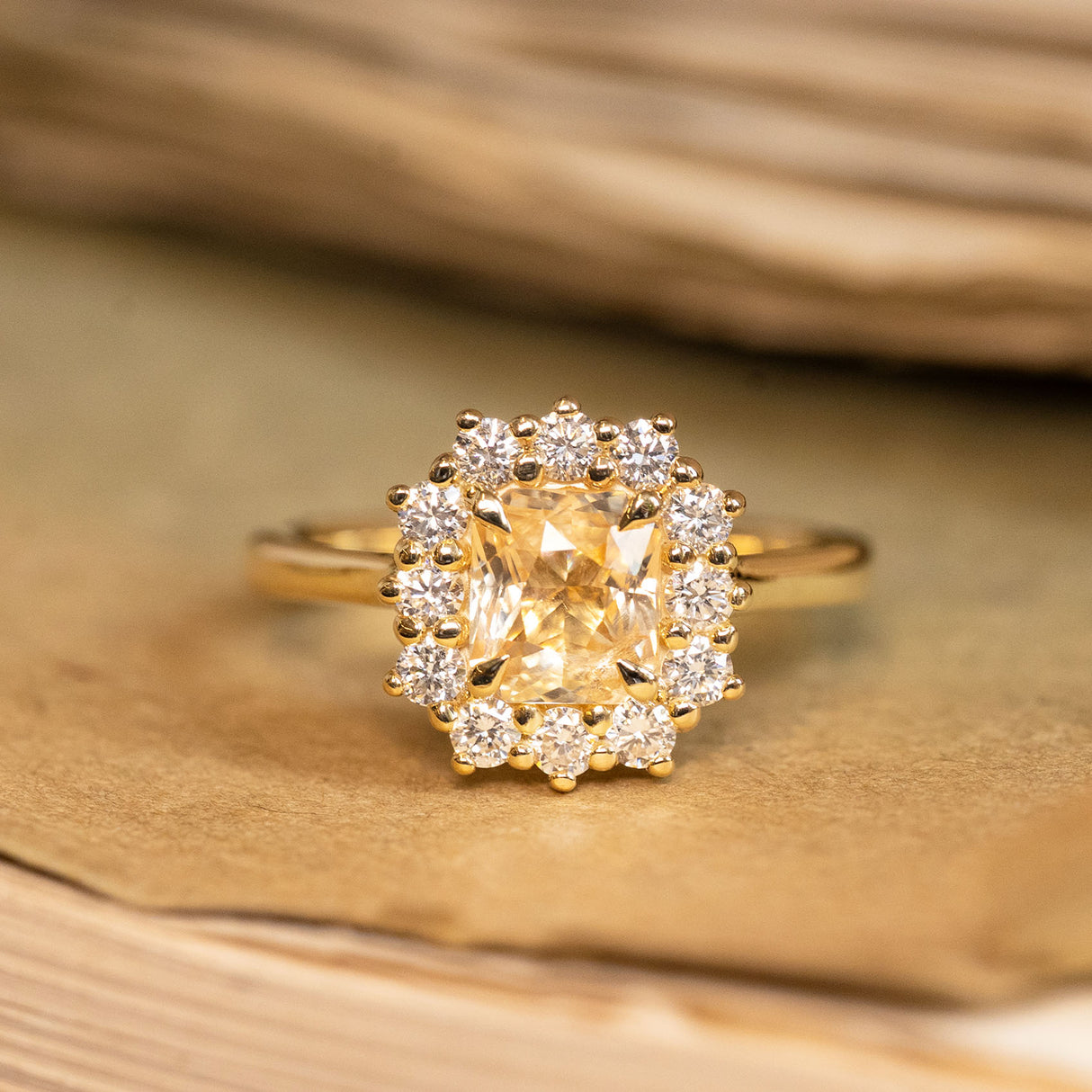 Yellow sapphire and diamond cluster engagement ring featuring a radiant yellow sapphire surrounded by brilliant-cut diamonds in yellow gold.