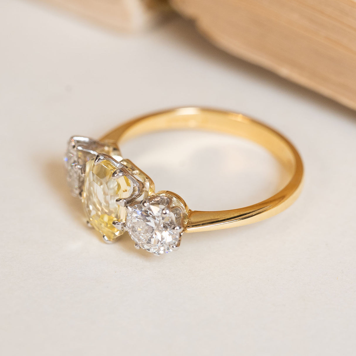 Vintage 1970s three-stone ring with an emerald-cut yellow sapphire flanked by old-cut diamonds in yellow and white gold.