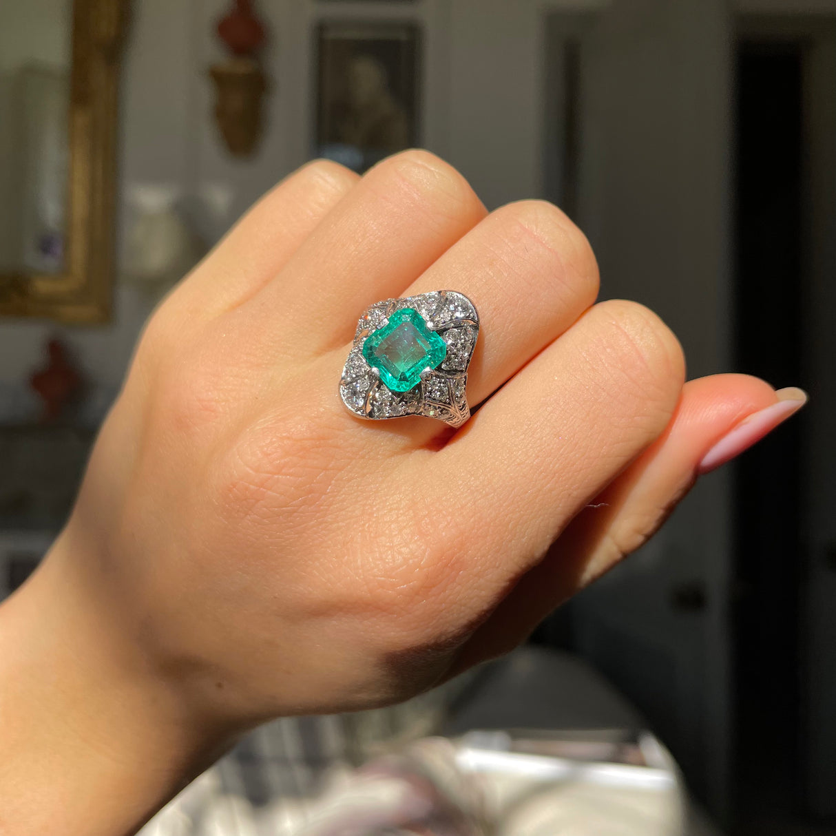 Art Deco emerald and diamond ring, worn on hand.