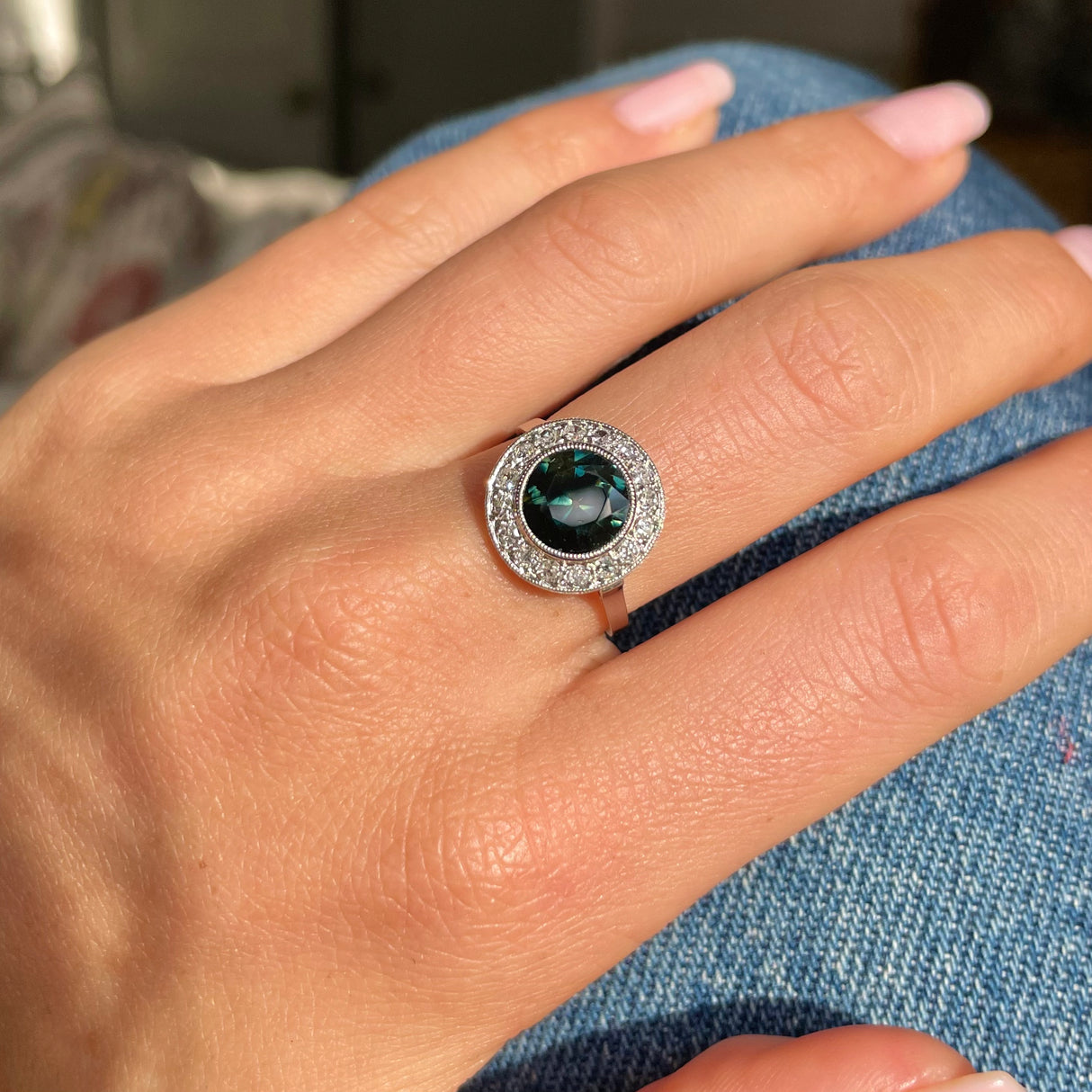 green yellow sapphire and diamond cluster ring, held in fingers.