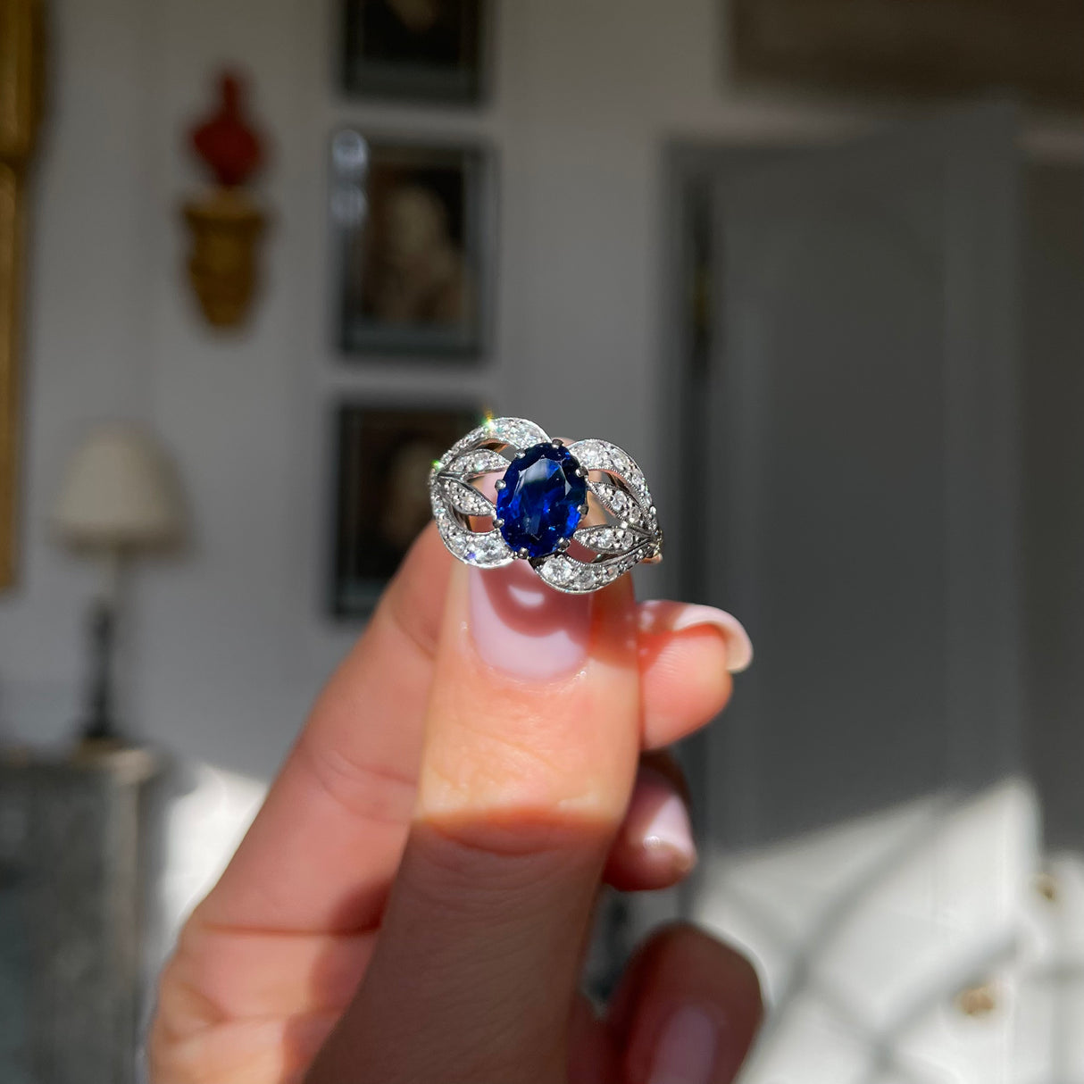 Art Nouveau, sapphire and diamond ring, held in fingers.