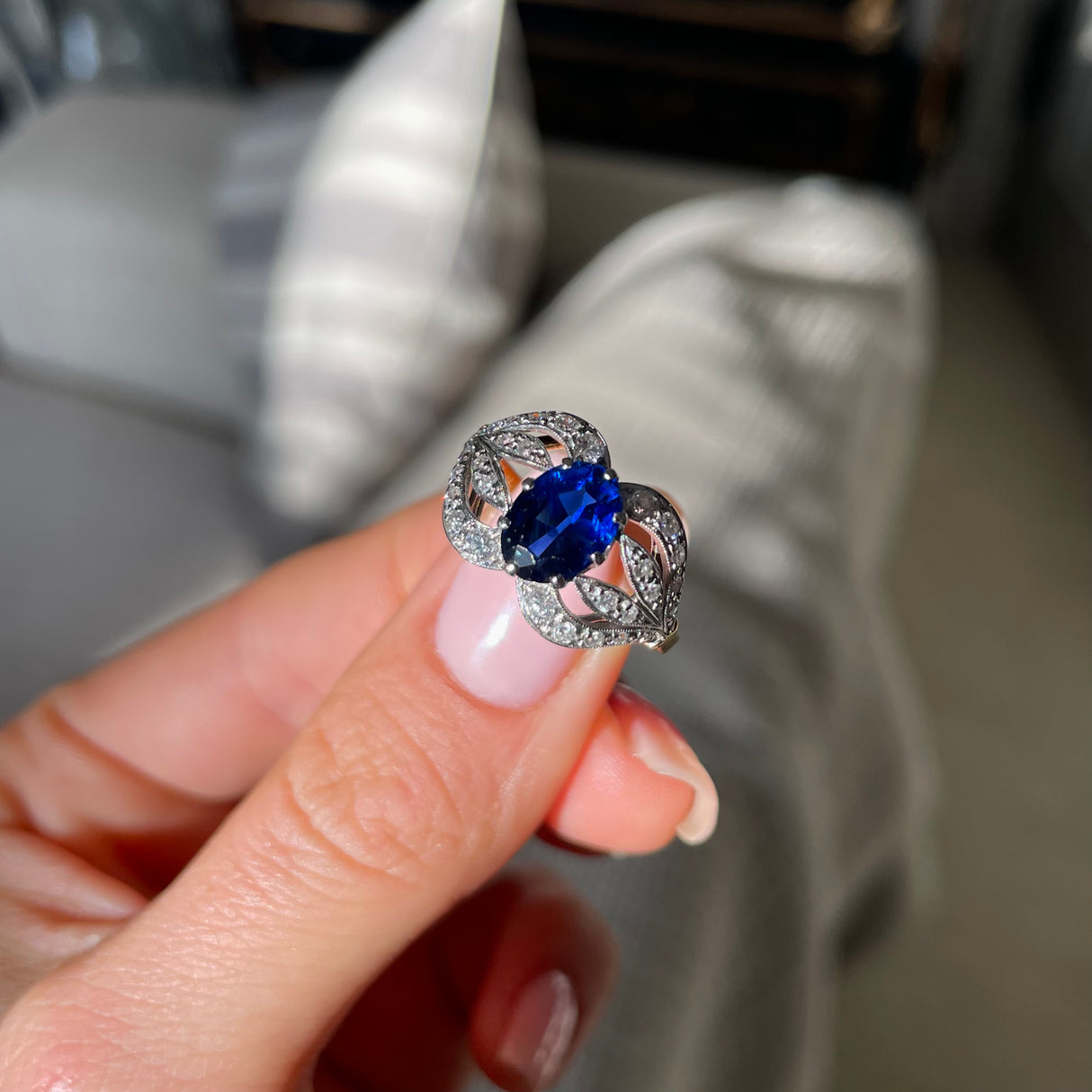 Art Nouveau, sapphire and diamond ring, held in fingers.