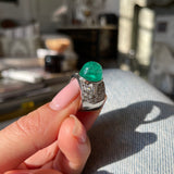 Trabert Hoeffer Mauboussin Art Deco emerald and diamond ring, held in fingers.