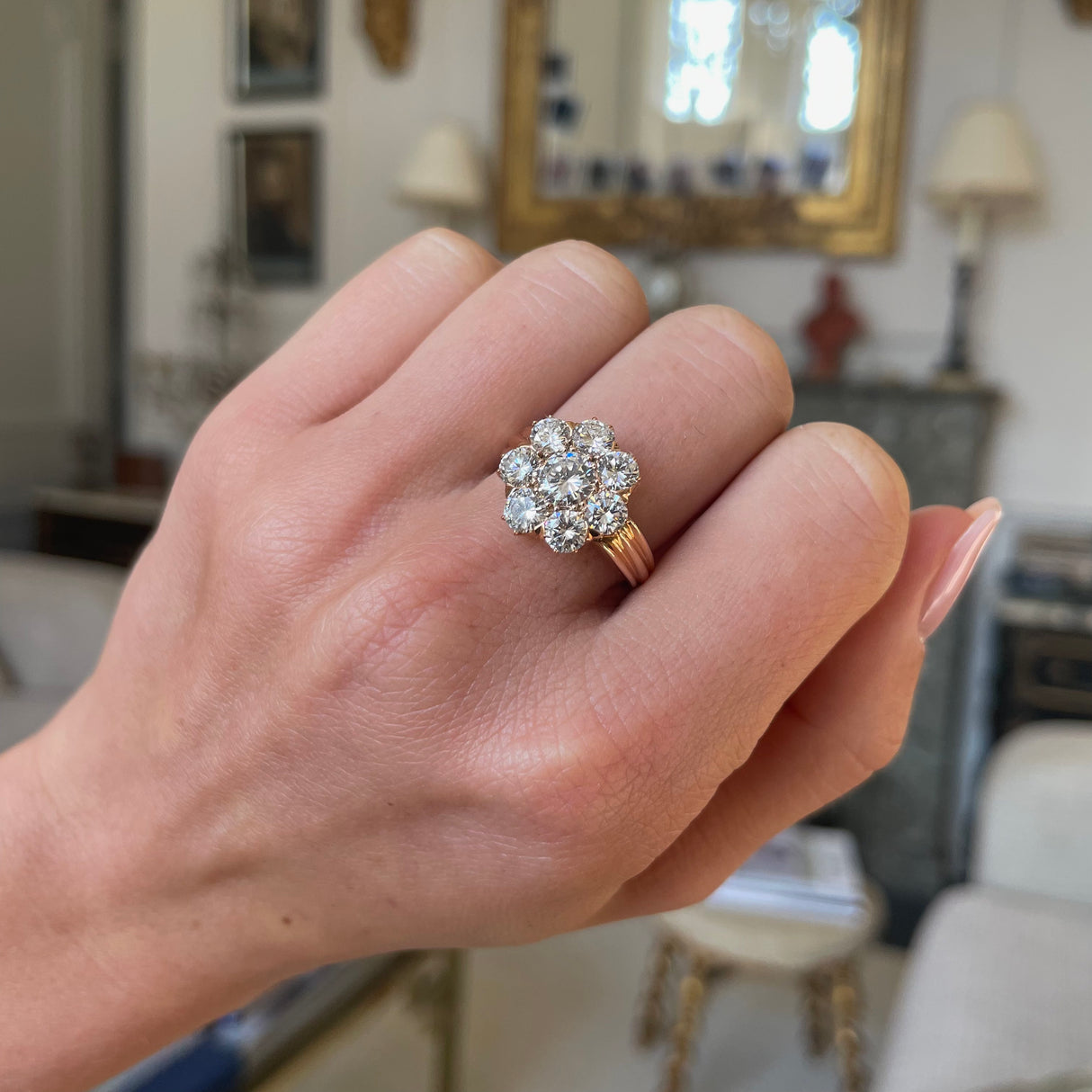 Edwardian diamond cluster engagement ring worn on closed hand. 